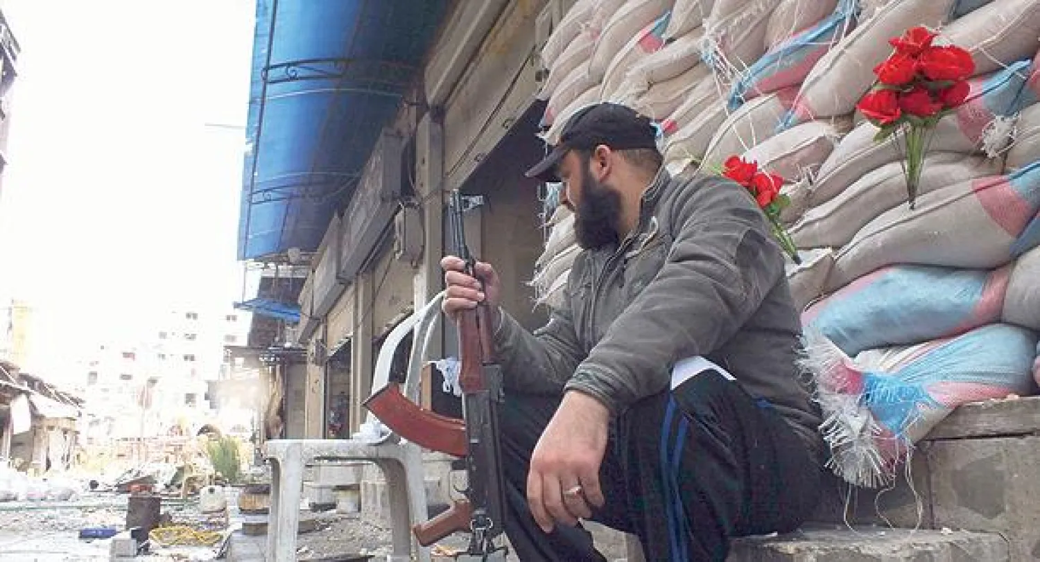 مقاتل في الجيش الحر يحرس موقعا في أحد شوارع حمص أمس (رويترز)