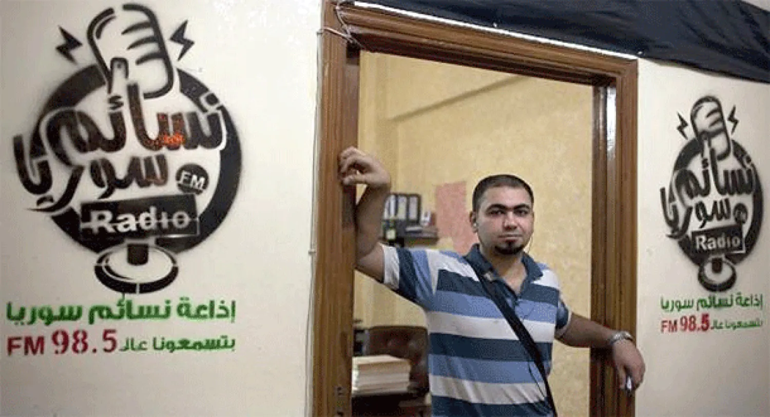 الشاب وائل عادل يقف أمام استديو إذاعة نسائم سوريا (أ.ف.ب)