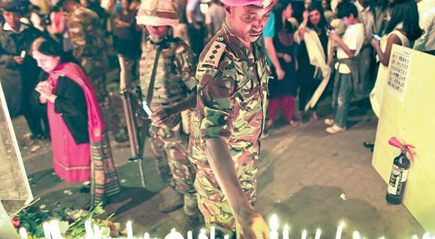 أفراد من الأمن الكيني يضعون الشموع أمام المبنى الذي تعرض للهجوم في نيروبي (إ.ب.أ)