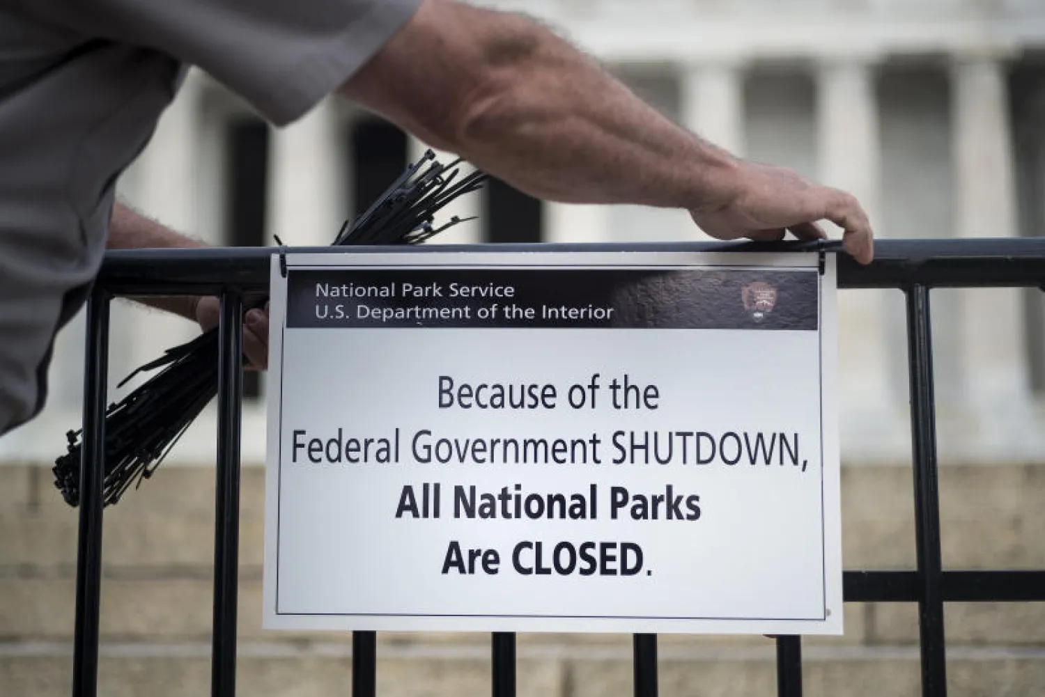 أحد حراس نصب لينكولن التذكاري في «ناشيونال مول» يضعون لافتة تشير إلى إغلاق الحديقة بقرار حكومي بعد فشل الكونغرس في الاتفاق على ميزانية العام الجديد (أ.ف.ب)