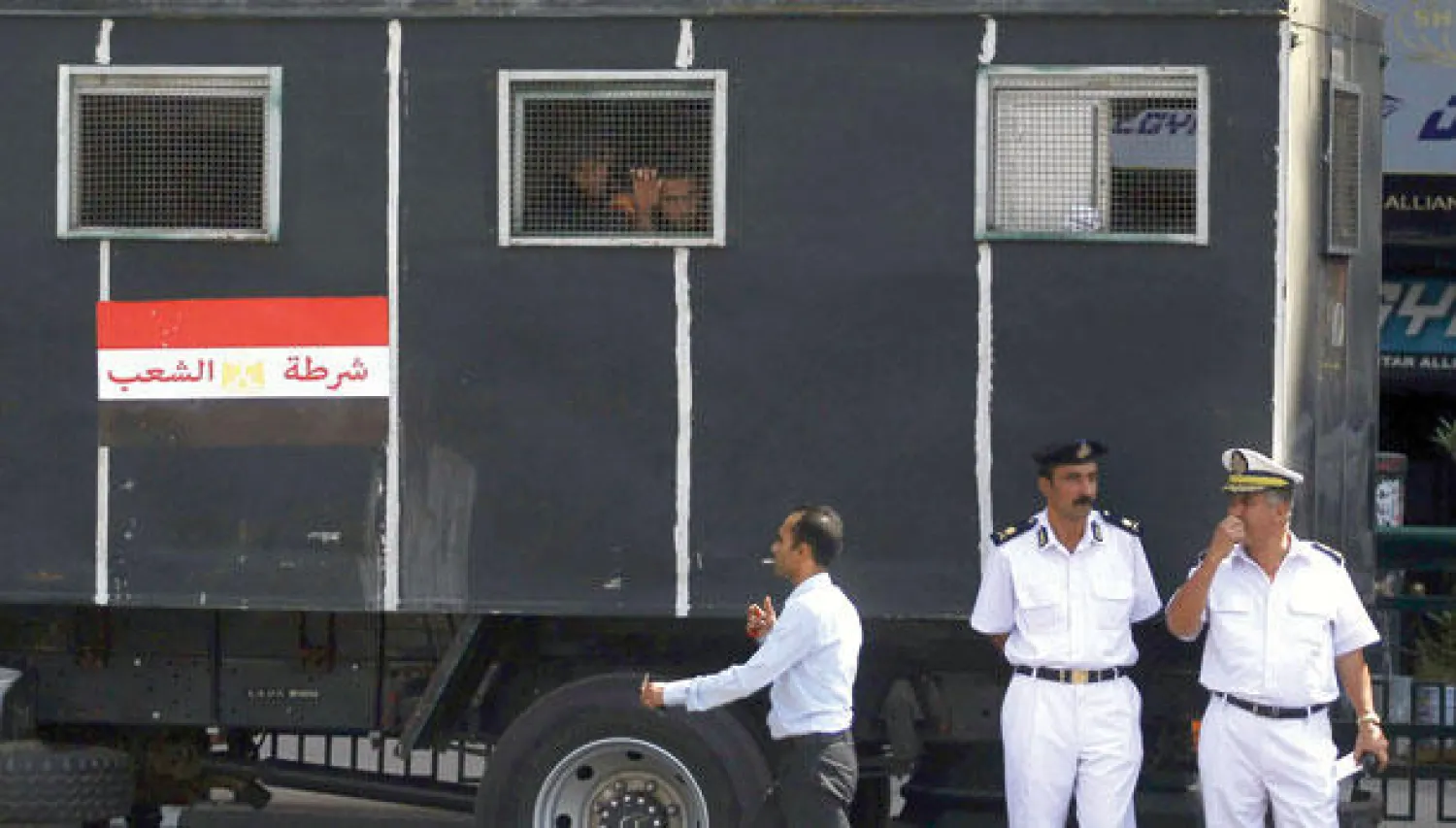 رجلا أمن يقفان بجانب شاحنة تابعة للشرطة ويبدو مجموعة من الذين تم إيقافهم أثناء مواجهات  بين محتجين ورجال الأمن بميدان التحرير أمس (رويترز)