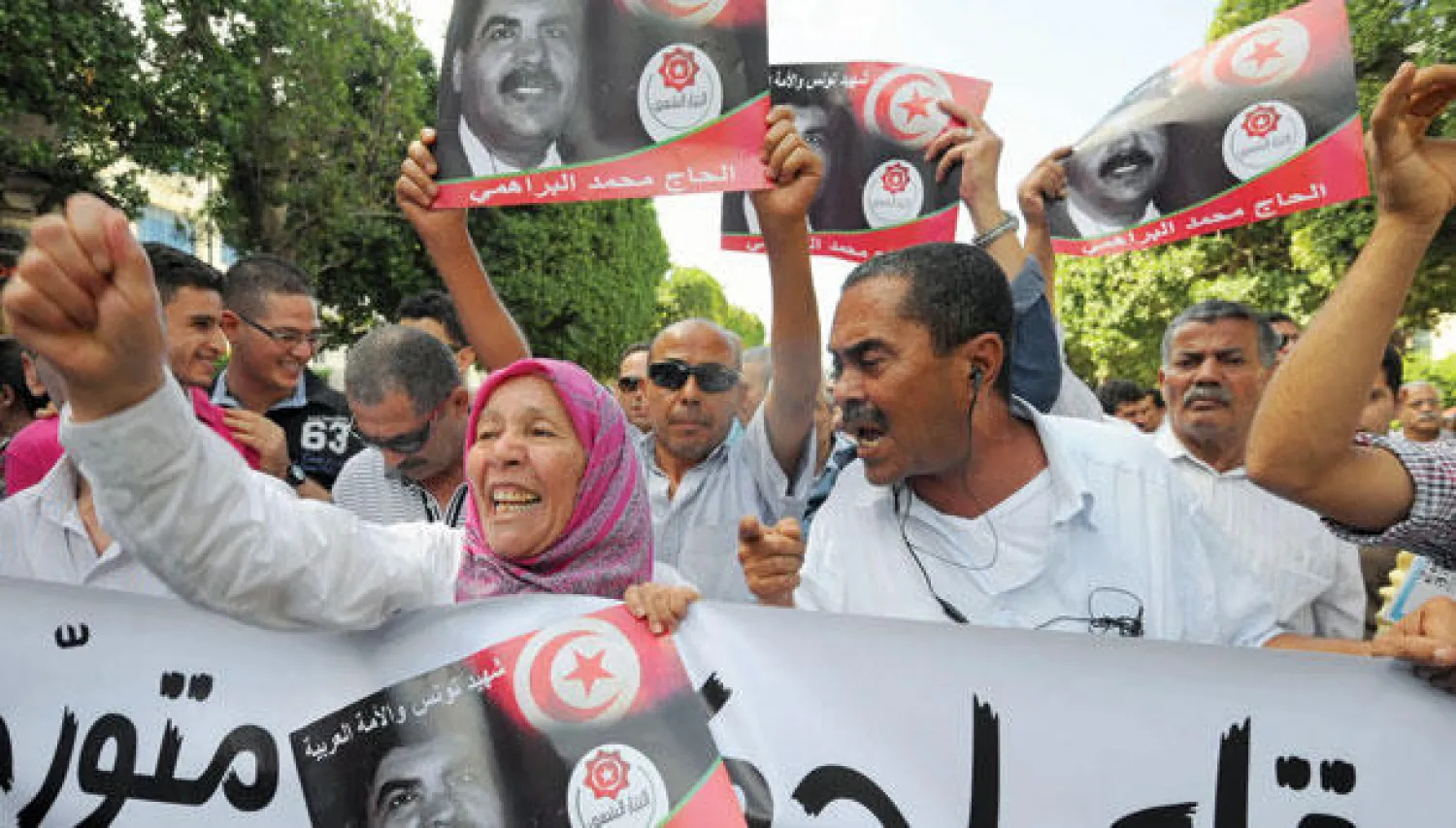 متظاهرون يطلقون شعارات أمس في تونس العاصمة ويرفعون صور النائب محمد البراهمي الذي اغتيل قبل أسابيع (أ.ف.ب)