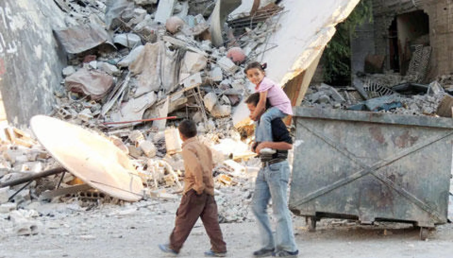 أطفال سوريون يمشون بحي زملكا بريف دمشق الذي تعرض لانفجار ضخم حوله إلى دمار أول من أمس  (رويترز)