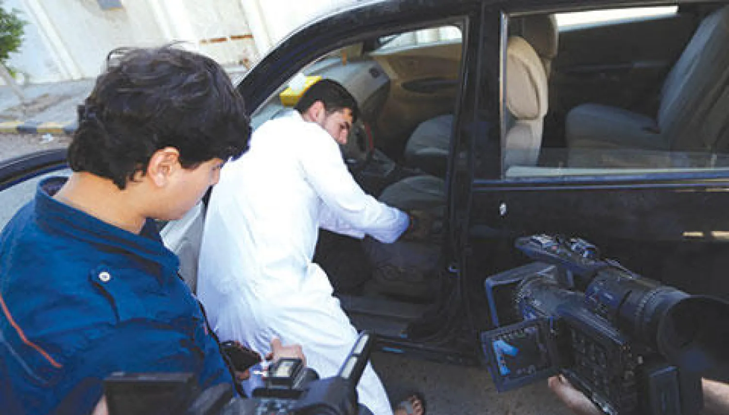 عبد الله وعبد المهيمن نجلا أبو أنس الليبي يفحصان سيارة والدهما في طرابلس أمس (أ.ف.ب)