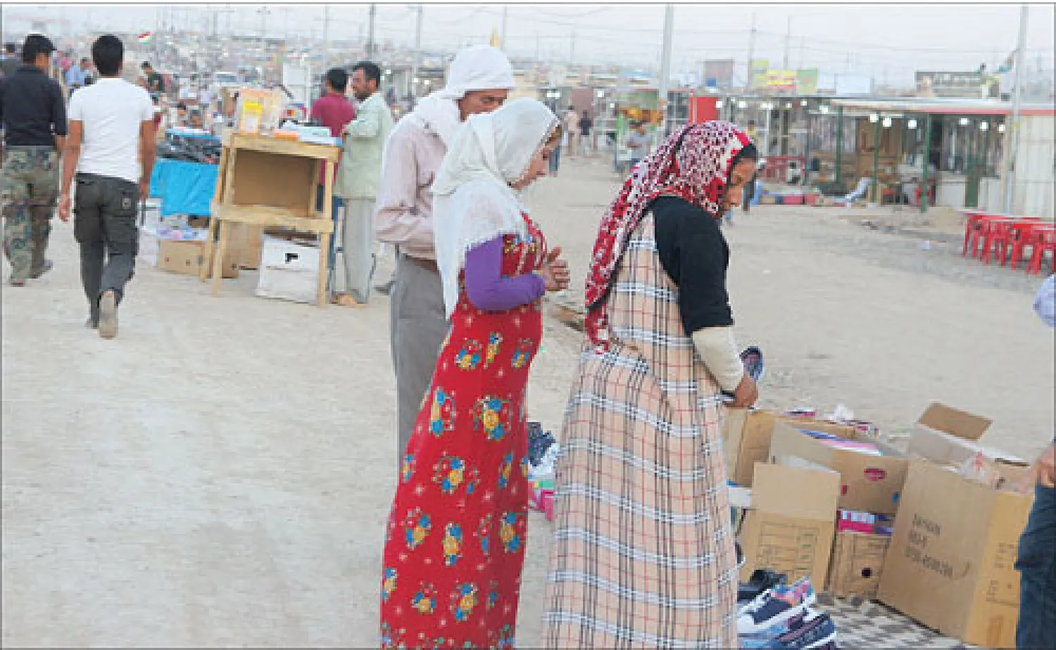 سوريتان تعاينان بضائع في سوق مخيم دوميز بمحافظة دهوك في إقليم كردستان العراق («الشرق الأوسط»)