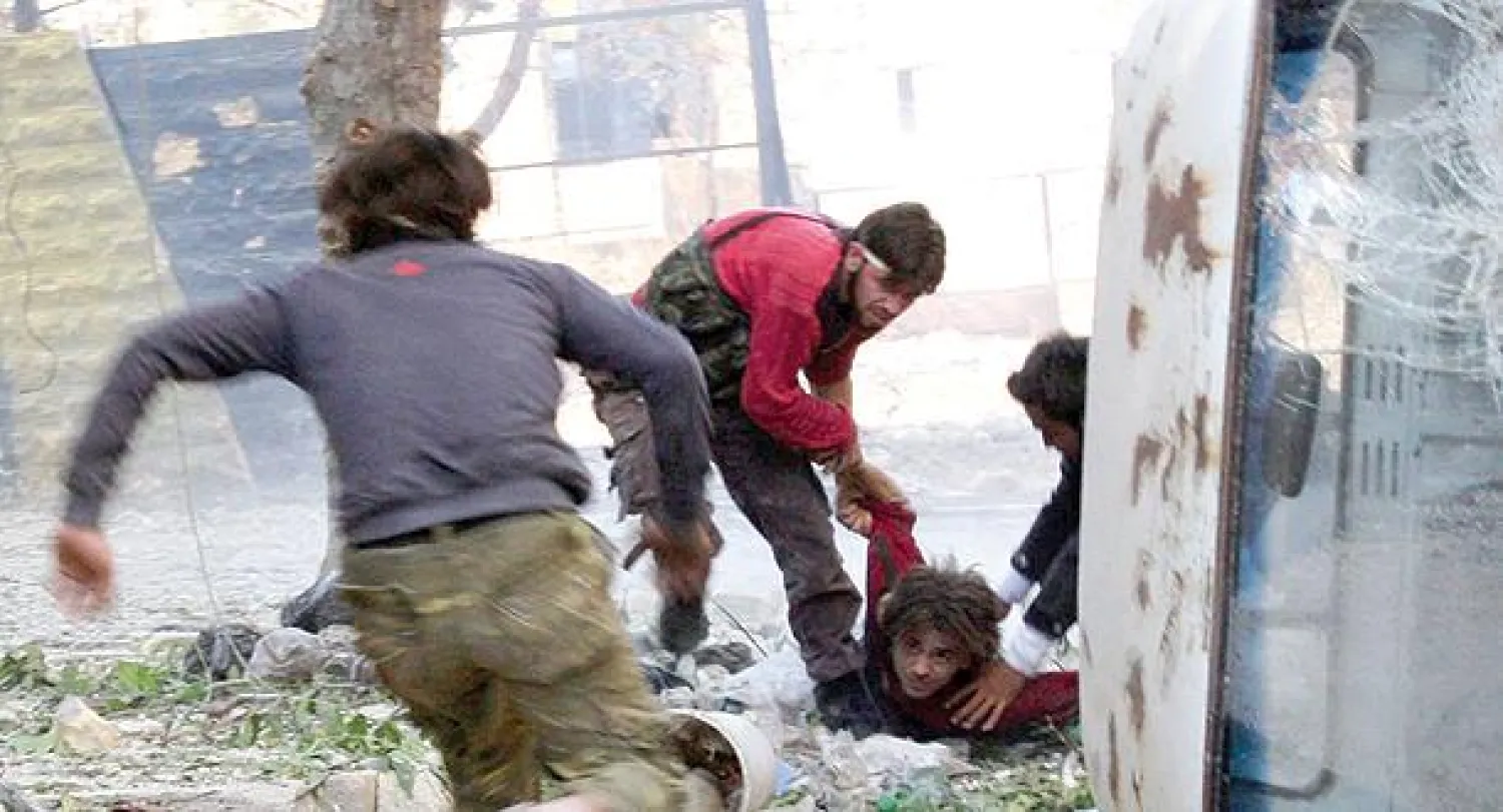 عناصر من الجيش السوري الحر المعارض يساعدون صبيا أصيب بنيران قناصة تابعين للنظام السوري في حلب أمس (رويترز)