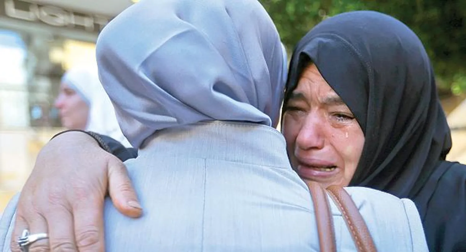 لاجئة سورية تنتحب وهي تودع قريبتها في بيروت أمس قبل أن تشد الرحال إلى المطار ومنه إلى ألمانيا ضمن دفعة جديدة من اللاجئين تستقبلها برلين (أ.ب)