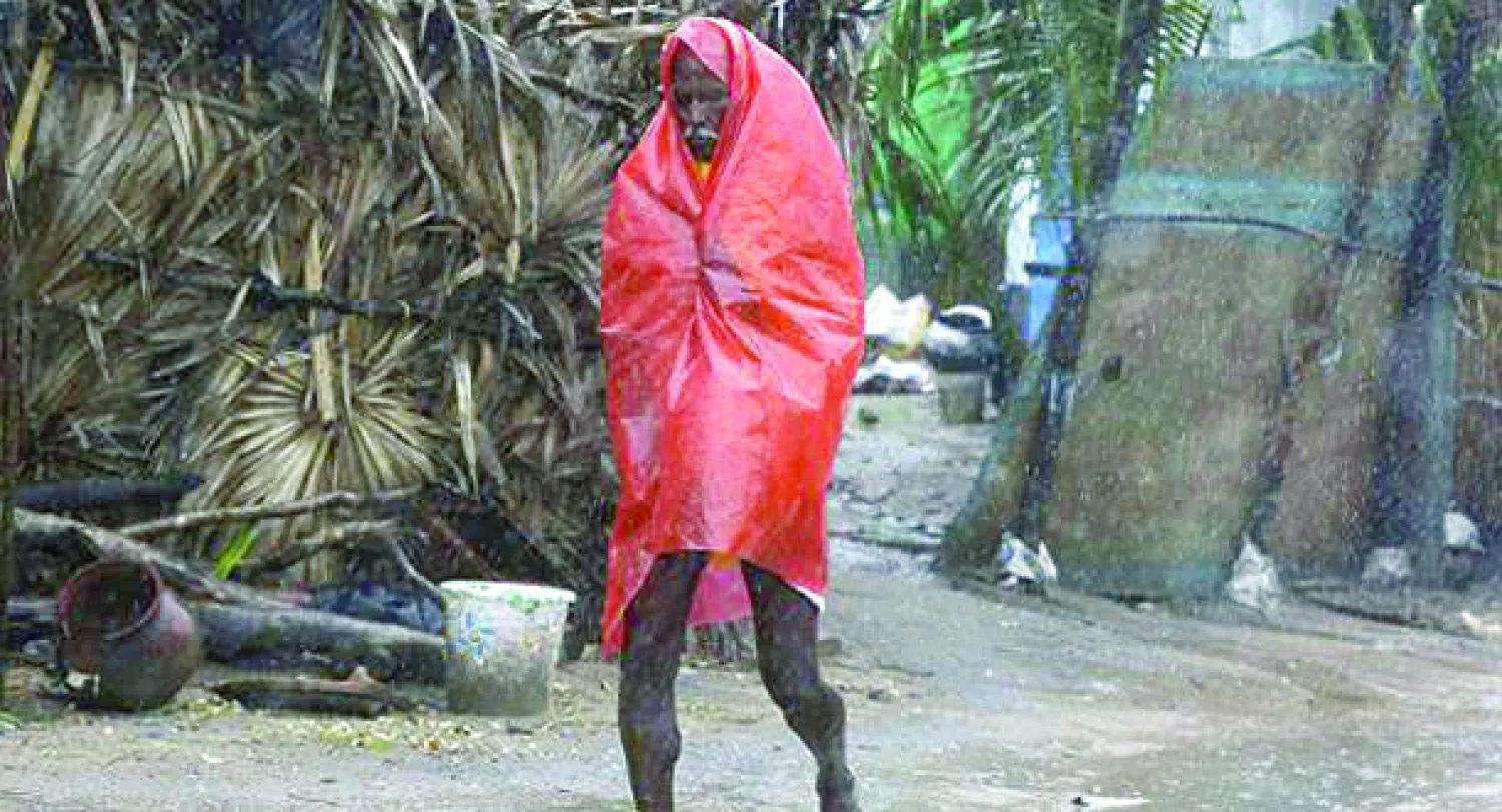 مسن يحتمي من البرد والرياح بغطاء بلاستيكي بعد إعصار ضرب الساحل الشرقي للهند اليوم (رويترز)
