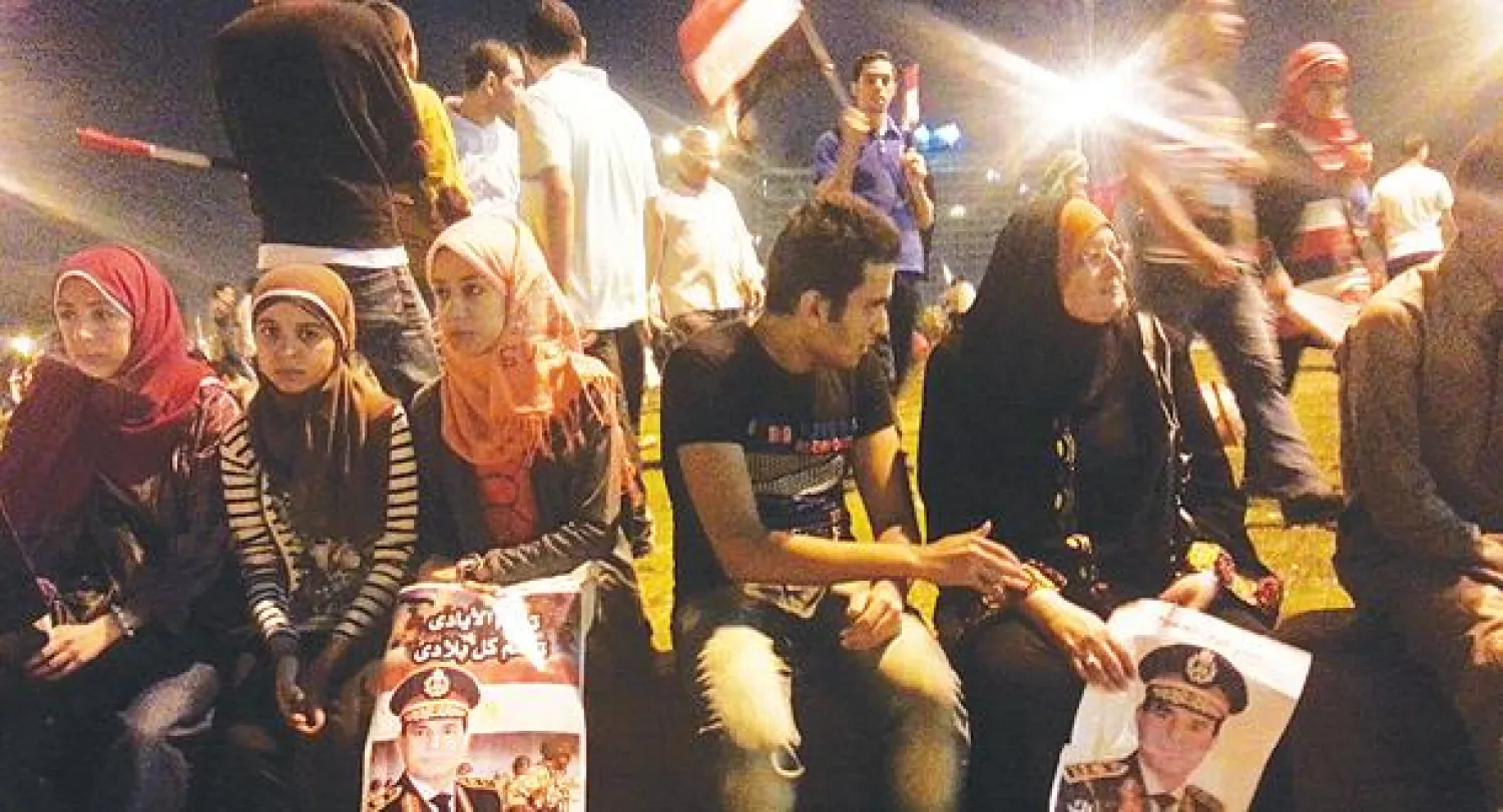 عائلة مصرية في ميدان التحرير تحمل صور قائد الجيش («الشرق الأوسط»)