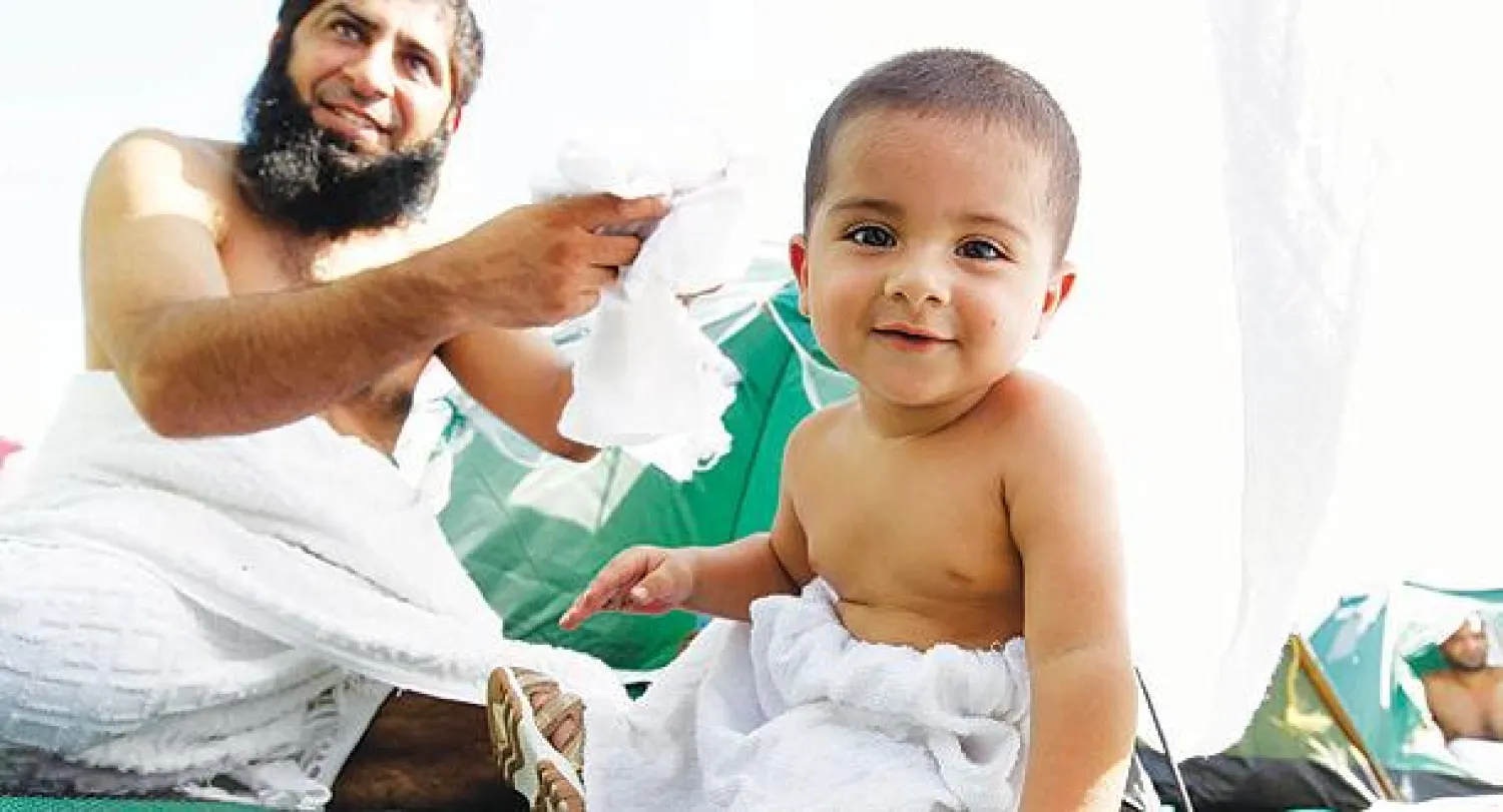 طفل مع والده في منى أمس  (تصوير: عبد الله آل محسن)