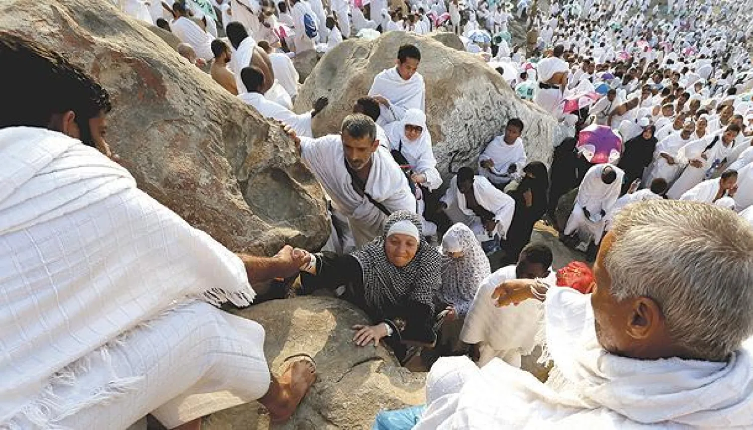 حجاج يساعدون حاجة على الصعود إلى جبل الرحمة في عرفات أمس (تصوير: خضر الزهراني)
