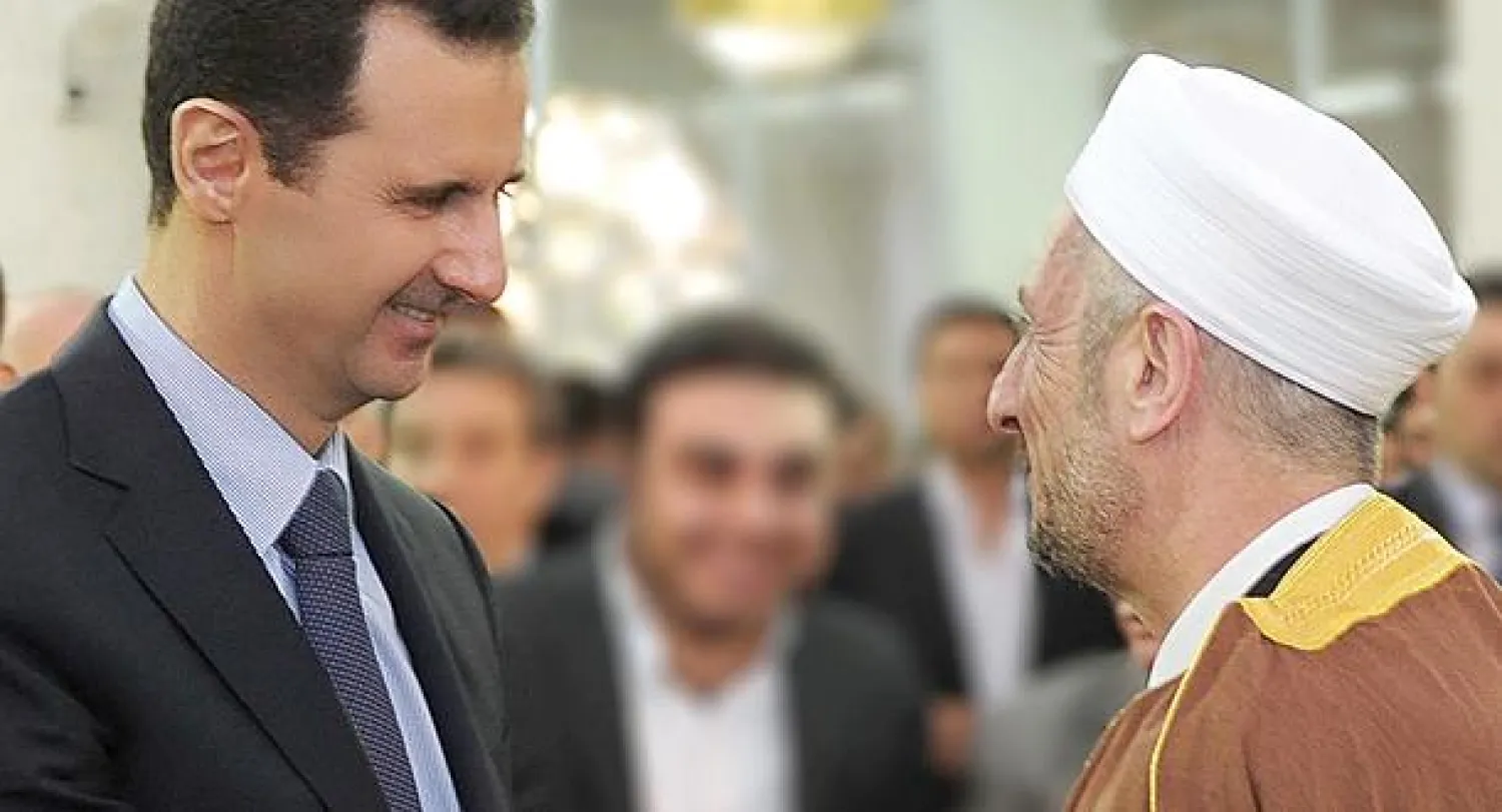 الرئيس السوري بشار الأسد يتحدث إلى الشيخ توفيق البوطي رئيس اتحاد علماء بلاد الشام  نجل الشيخ رمضان البوطي الذي قتل في أبريل الماضي بعد صلاة عيد الأضحى أمس (أ. ف.ب)