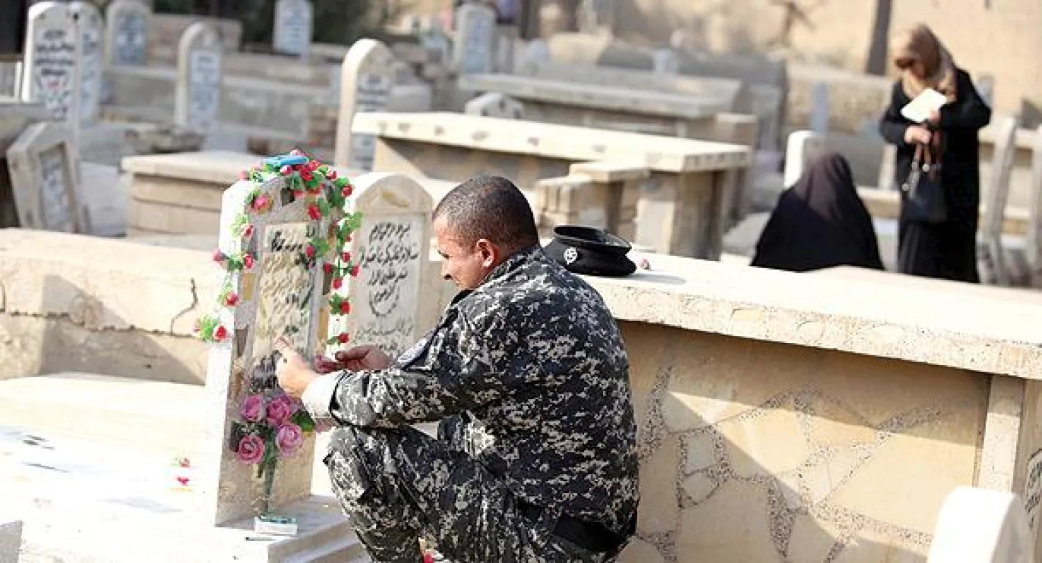 رجل شرطة عراقي يزور قبر زوجته التي قتلها مسلحون في العاصمة بغداد أمس (أ.ف.ب)