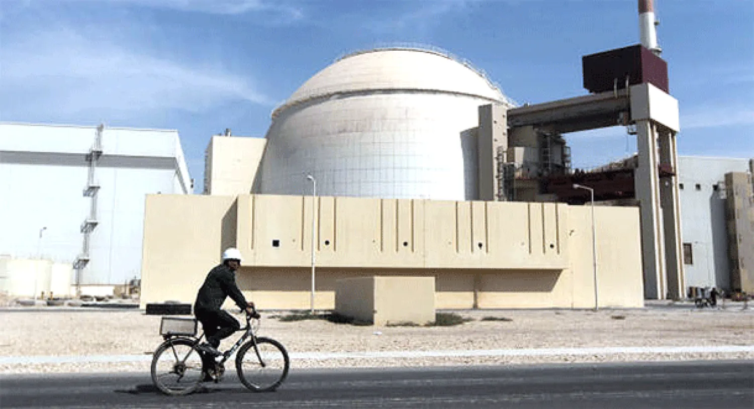 عامل بدراجة هوائية يمر أمام مبنى في منشأة بوشهر النووية (أ.ب)