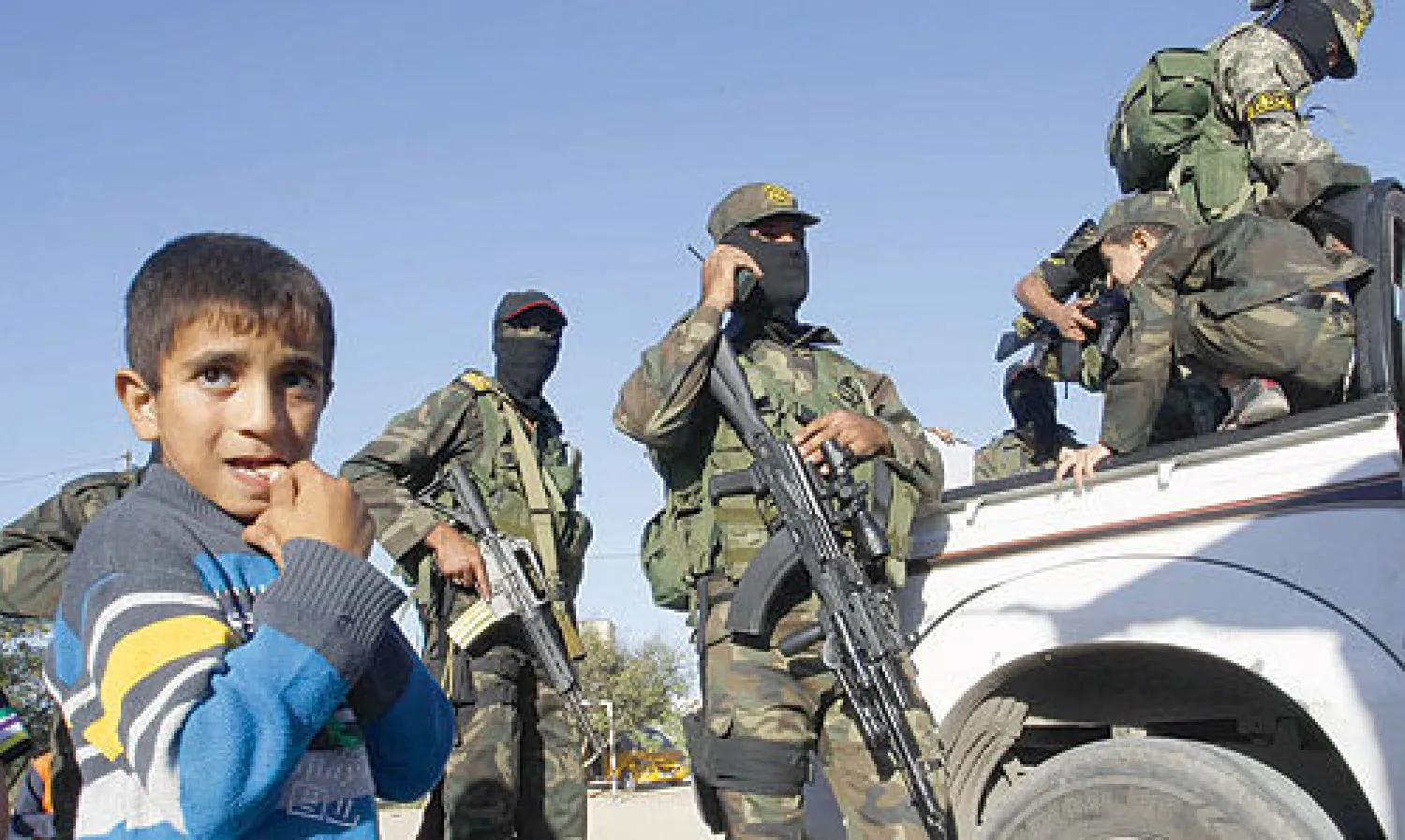 طفل فلسطيني يقف الى جانب مسلحين من «الجهاد الاسلامي» في قطاع غزة أمس (أ.ف.ب)