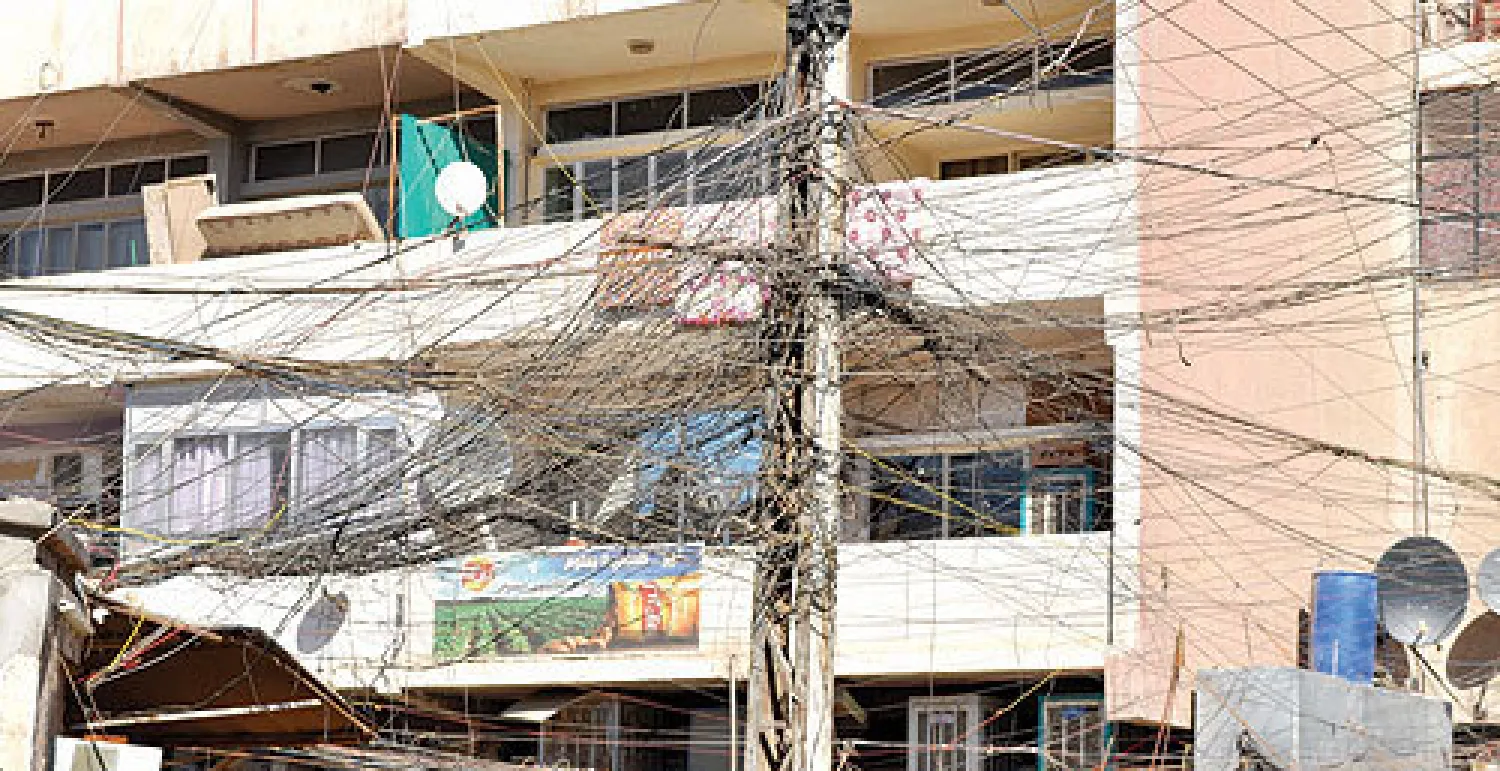 أسلاك كهربائية تتدلى في حي الكرادة (داخل) وسط بغداد لتوصيل الطاقة إلى البيوت بأسعار عالية («الشرق الأوسط»)