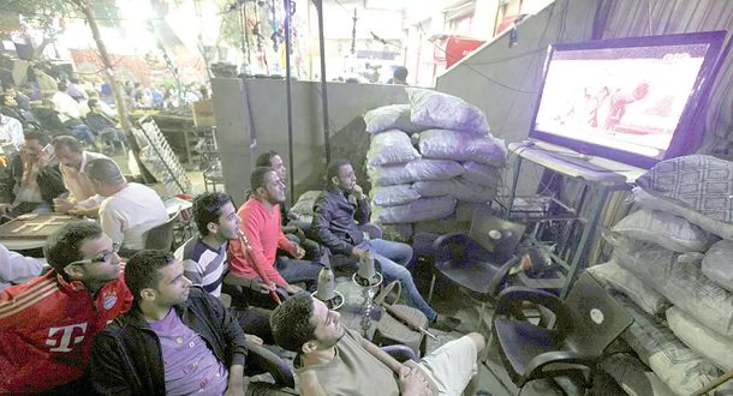 مواطنون مصريون في وسط القاهرة ليلة أول من أمس يتابعون حلقة جديدة من برنامج «البرنامج» تقديم الإعلامي الساخر باسم يوسف (رويترز)