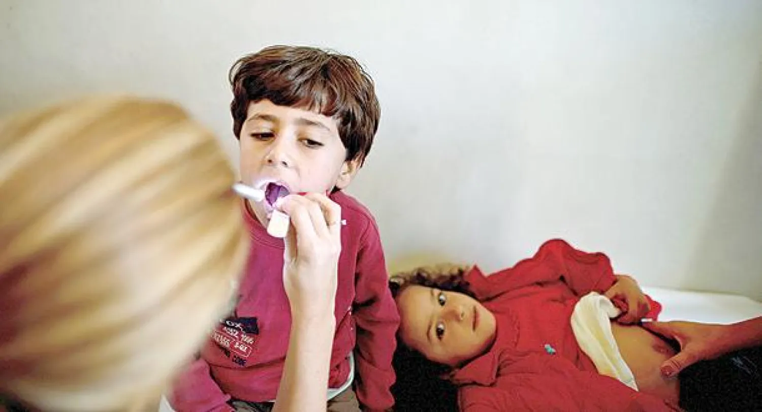 طبيبة بلغارية تفحص طفلا سوريا في مخيم لاجئين بالعاصمة صوفيا أمس (إ.ب.أ)