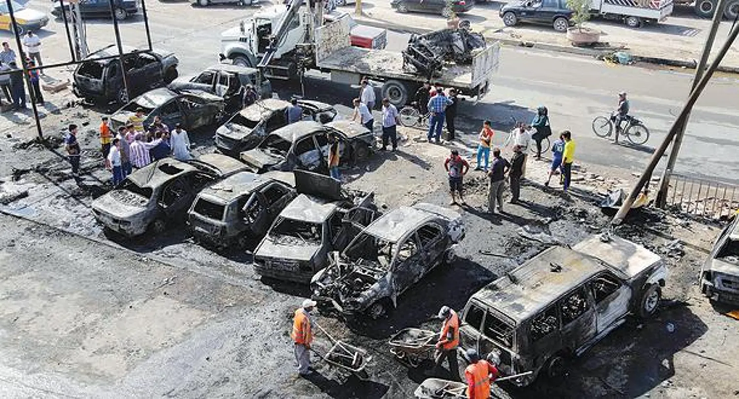 عمال البلدية يزيلون الأنقاض من موقع انفجار سيارة مفخخة في بغداد أمس (أ.ب)