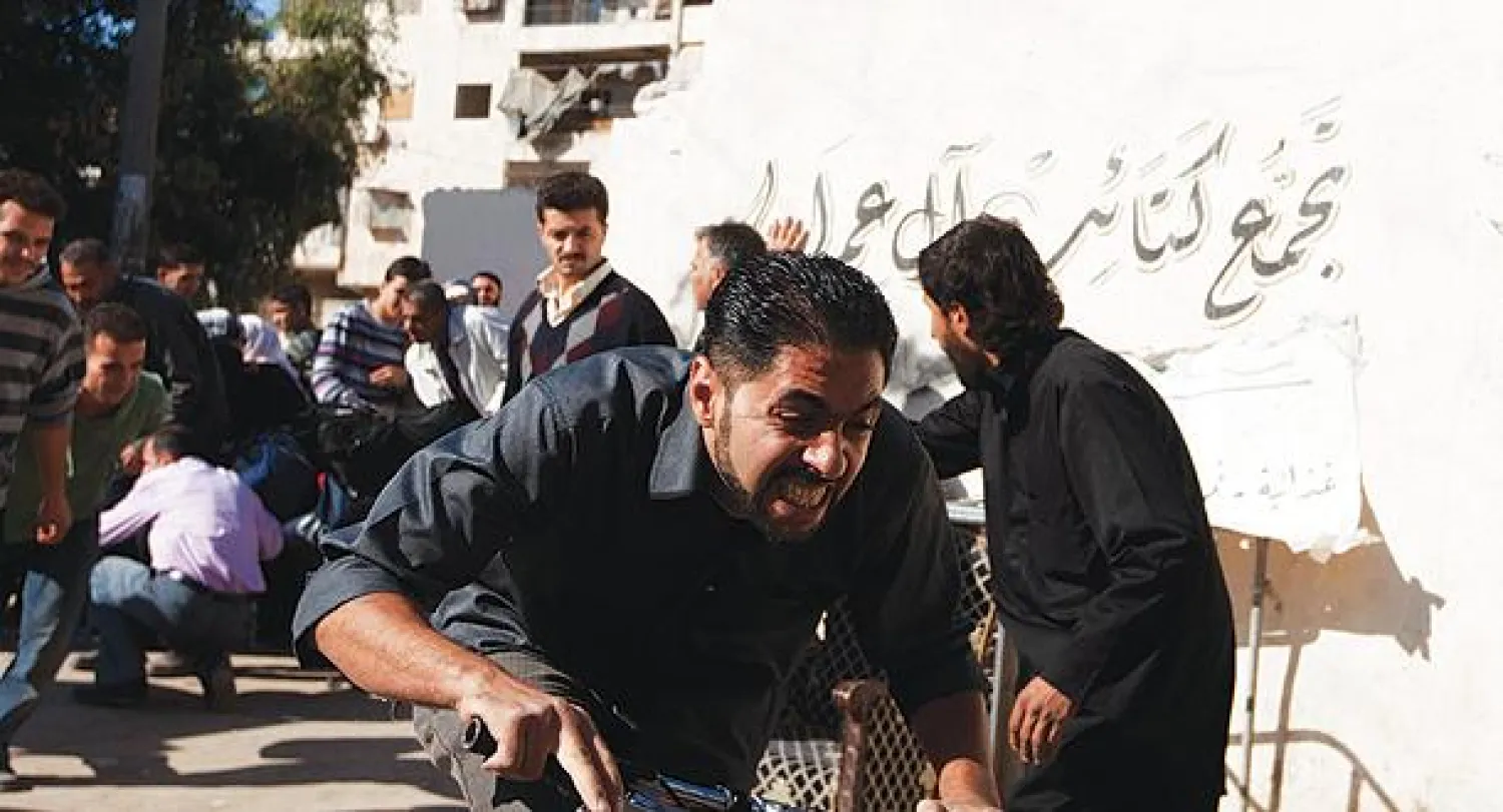 مقاتل سوري يتحاشى نيران قناص في نقطة تفتيش ببستان القصر في حلب (رويترز)
