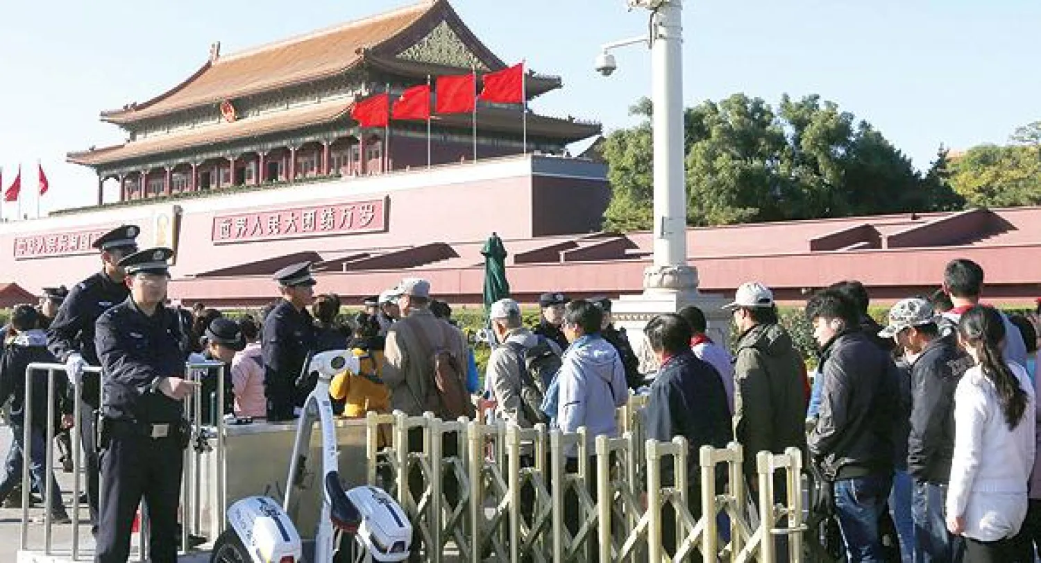 الشرطة تراقب الوضع أمام زوار ينتظرون في طابور لولوج القصر الإمبراطوري  (المدينة المحرمة) في ساحة تيان أنمين ببكين أمس (إ.ب.أ)