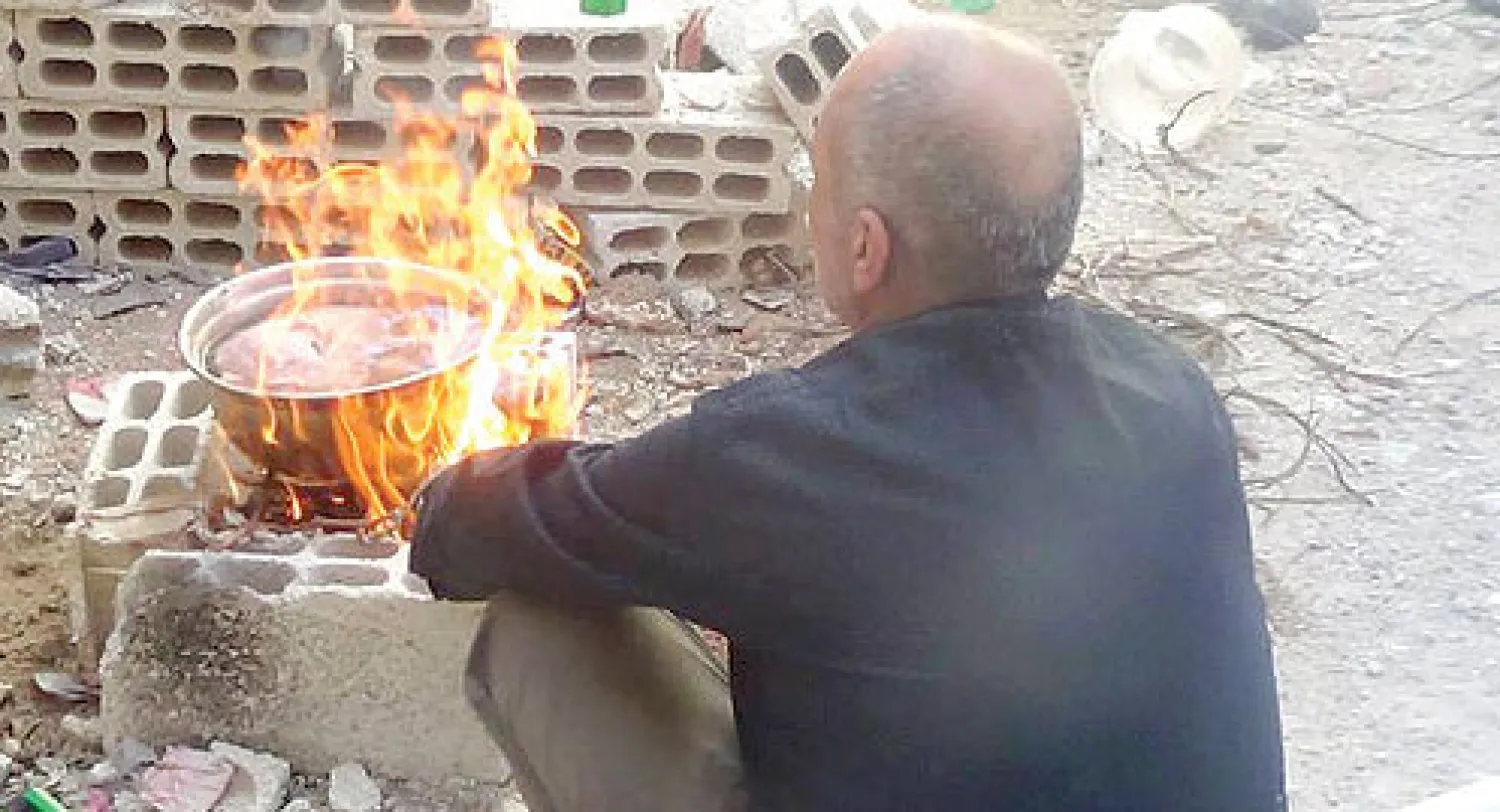 صورة وزعها موقع معارض لسوري يطهو قطا في مخيم اليرموك المحاصر جنوب دمشق («الشرق الأوسط»)