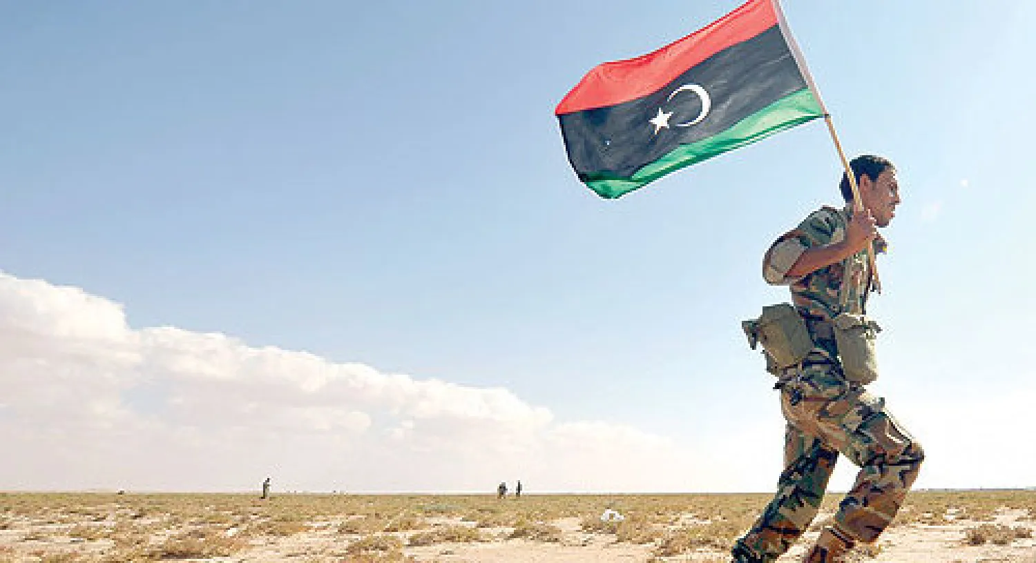 جندي ليبي يحمل علم بلاده أثناء تأديته امتحانا عمليا لتخرجه في منطقة قمينس قرب بنغازي (رويترز)