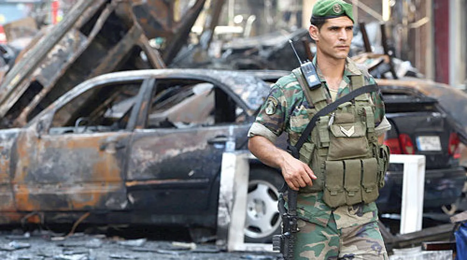 عنصر في الجيش اللبناني يمر من امام سيارات احترقت بسبب التفجير الهائل الذي حدث في منطقة الرويس بضاحية بيروت معقل حزب الله في اغسطس الماضي (أ.ب)