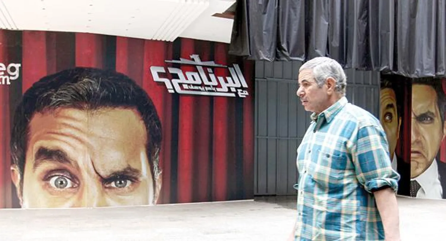 مواطن مصري يمر بجوار ملصق إعلاني ضخم لبرنامج «البرنامج» الذي يقدمه الإعلامي الساخر باسم يوسف قبل منعه  مساء أول من أمس (إ.ب.أ)