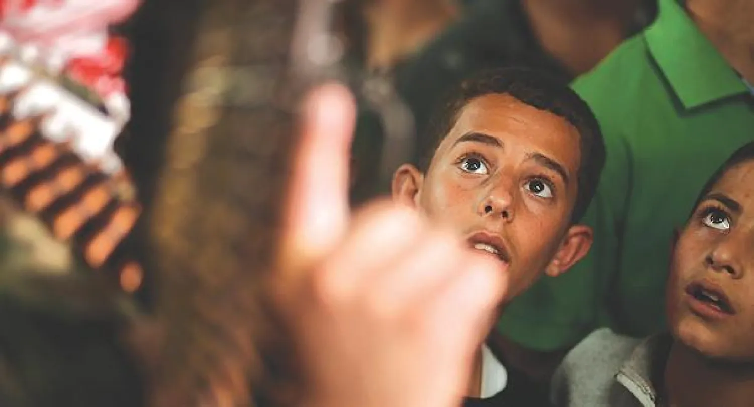 صبيان فلسطينيان يعاينان عنصرا في حماس خلال تشييع قيادي في الحركة  قضى في غارة إسرائيلية بخان يونس جنوب غزة أمس (رويترز)