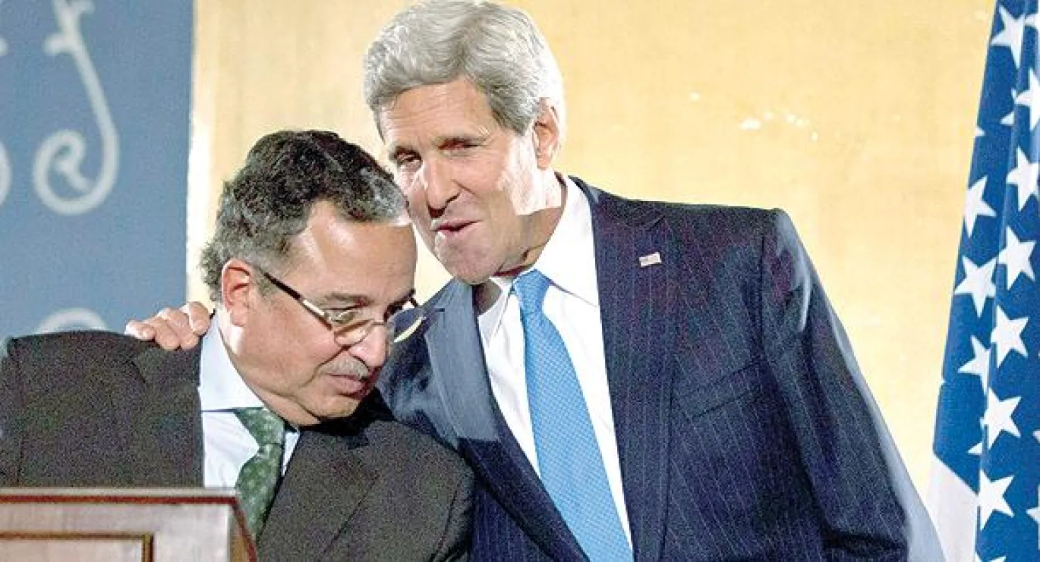 وزير الخارجية الأميركي جون كيري يهمس في أذن نظيره المصري نبيل فهمي خلال مؤتمر صحافي مشترك بالقاهرة أمس (رويترز)