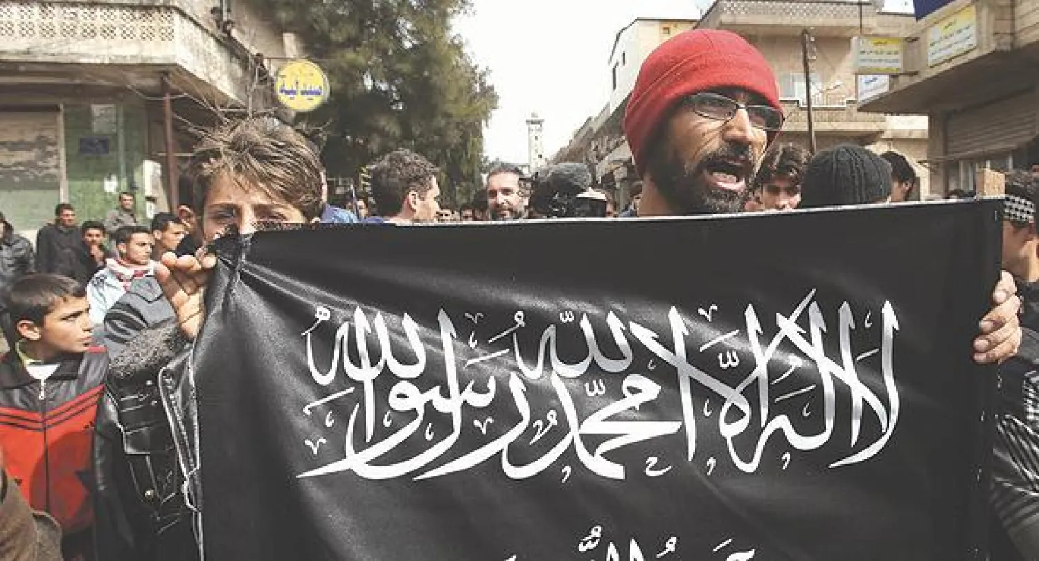 موالون لجبهة النصرة يرفعون علمها خلال مظاهرة في كفرنبل بمحافظة إدلب ضد نظام الأسد (أ.ب)