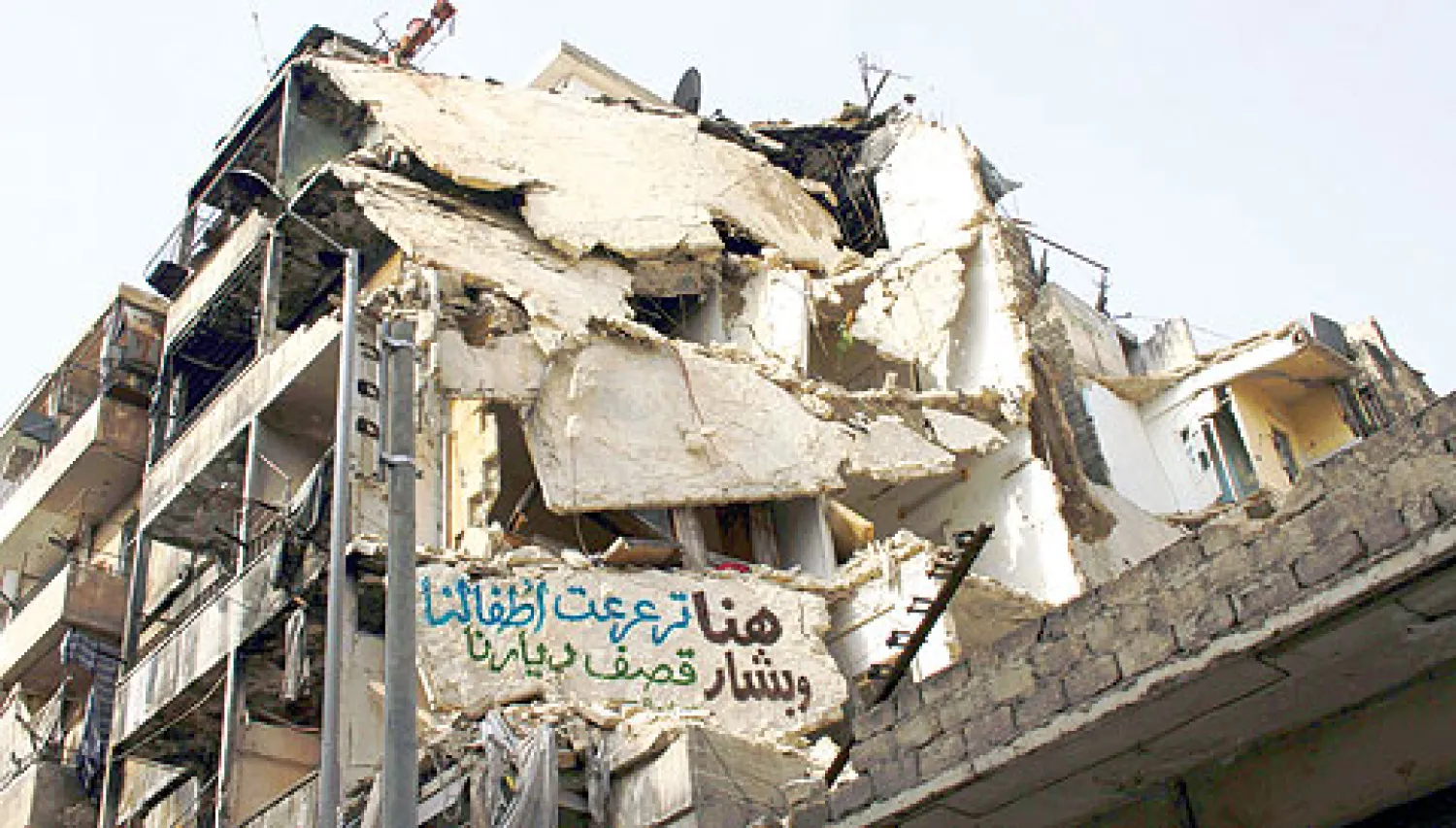 عمارة سكنية في حلب دمرتها قوات النظام علقت على انقاضها يافطة كتب عليها {هنا ترعرع أطفالنا وبشار قصف ديارنا} (أ.ف.ب)