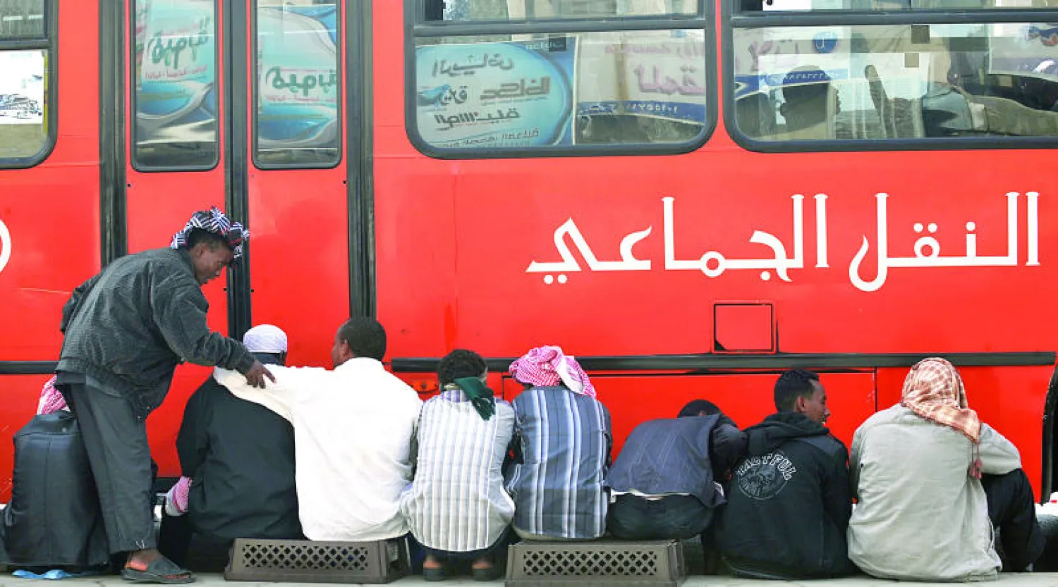 عمال أجانب في انتظار ترحيلهم الى أحد مراكز تجميع المخالفين لنظم العمل والإقامة في الرياض أمس (أ.ف.ب) 