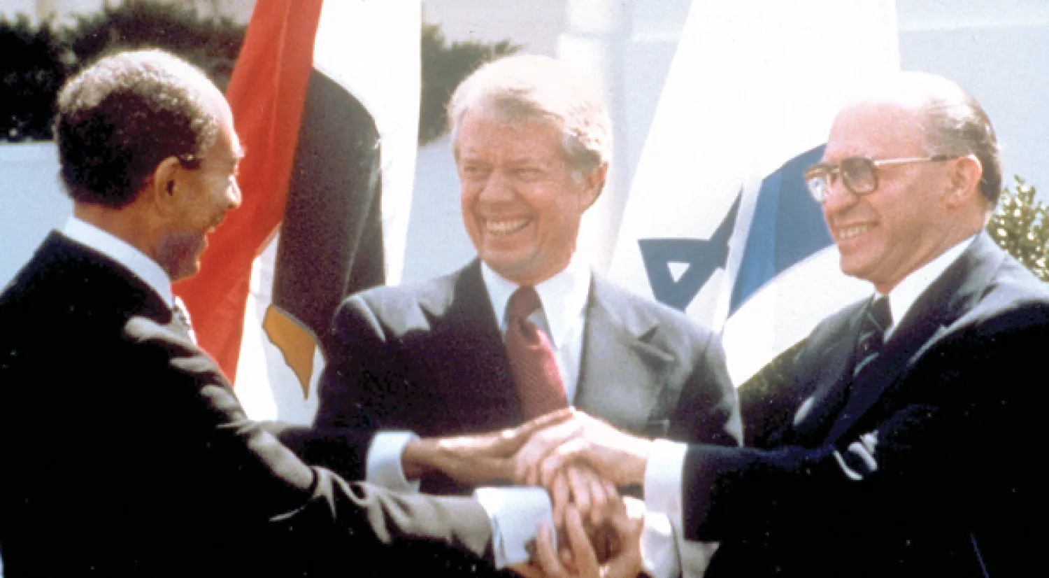 الرئيسان الأميركي جيمي كارتر والمصري أنور السادات ورئيس الوزراء الإسرائيلي مناحم بيغن يشبكون أياديهم عقب التوقيع النهائي على معاهدة السلام في البيت الأبيض الأميركي في 26 مارس 1979 (أ.ب)