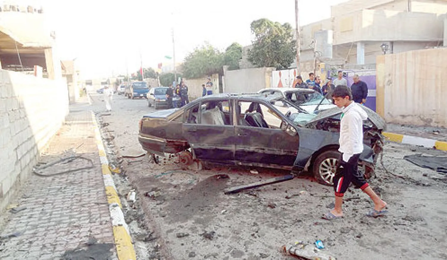 عراقي يتفحص سيارة انفجرت في حي سكني وسط مدينة كركوك التي تضم سنة من العرب والتركمان والأكراد (أ.ف.ب)