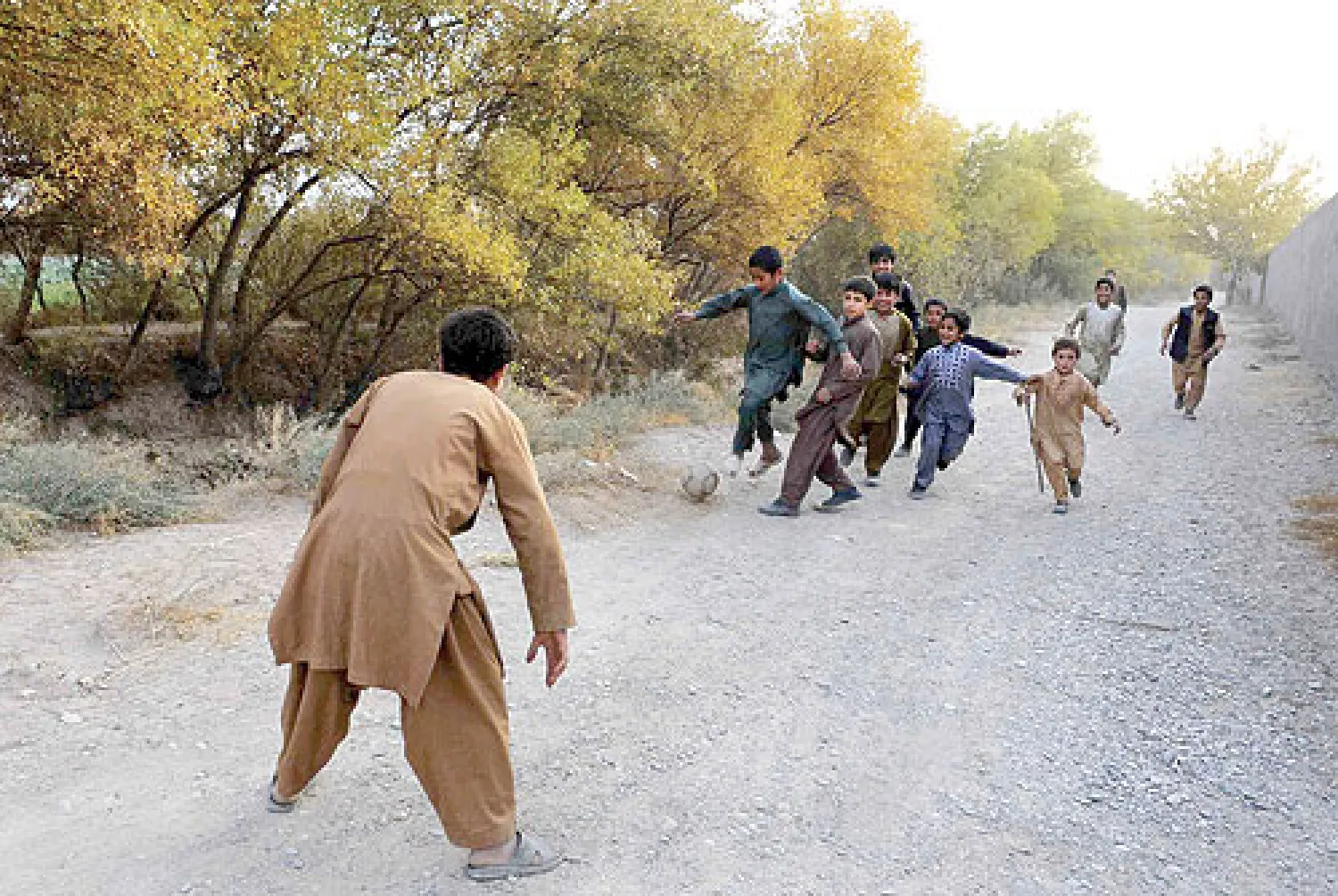 أطفال يعلبون الكرة في طريق عام بمدينة هراة غرب أفغانستان أمس (أ.ف.ب)