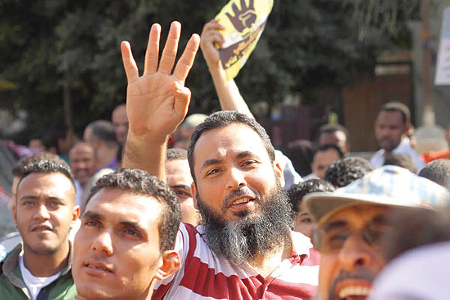 متظاهر مؤيد لـ«الإخوان» يرفع يده بشعار «رابعة» في أحد ميادين القاهرة أمس (أ.ب)