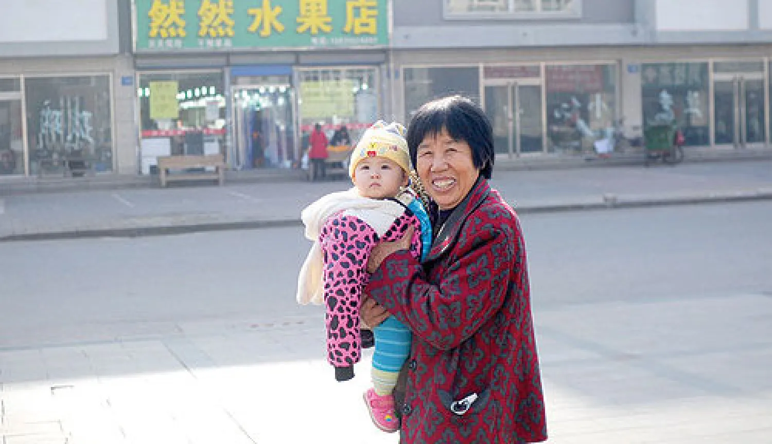 صينية تبدو على ملامحها السعادة وهي تسير حاملة طفلا في احد شوارع تانغ شان في اقليم هوبي شمال الصين في ظل الانباء عن تغيير الحزب الشيوعي الصيني لسياسة الطفل الواحد (أ.ف.ب)
