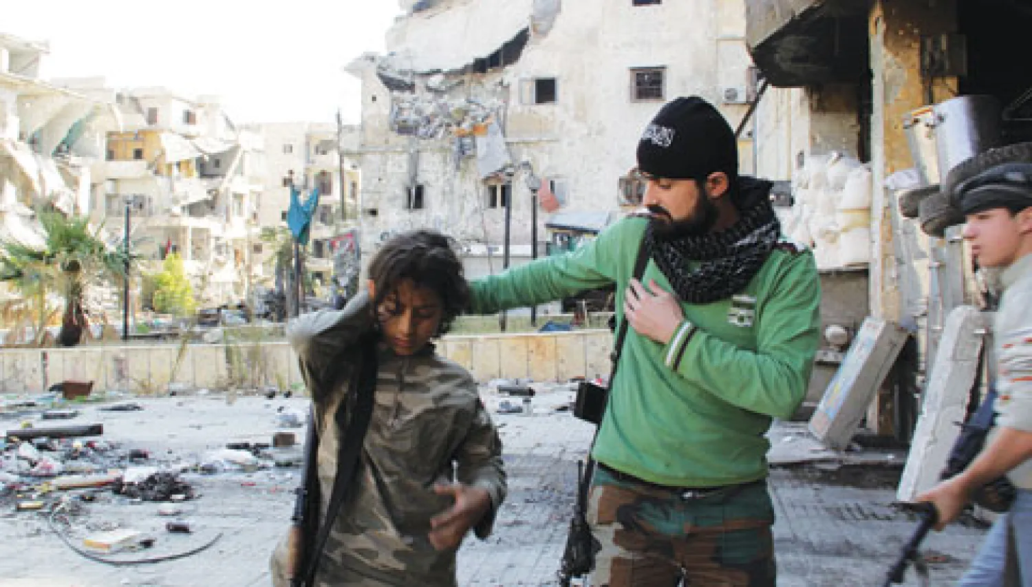 مقاتل سوري يساعد صبيين قبل انطلاقهم في دورية في حي صلاح الدين بمدينة حلب أمس (أ.ف.ب)