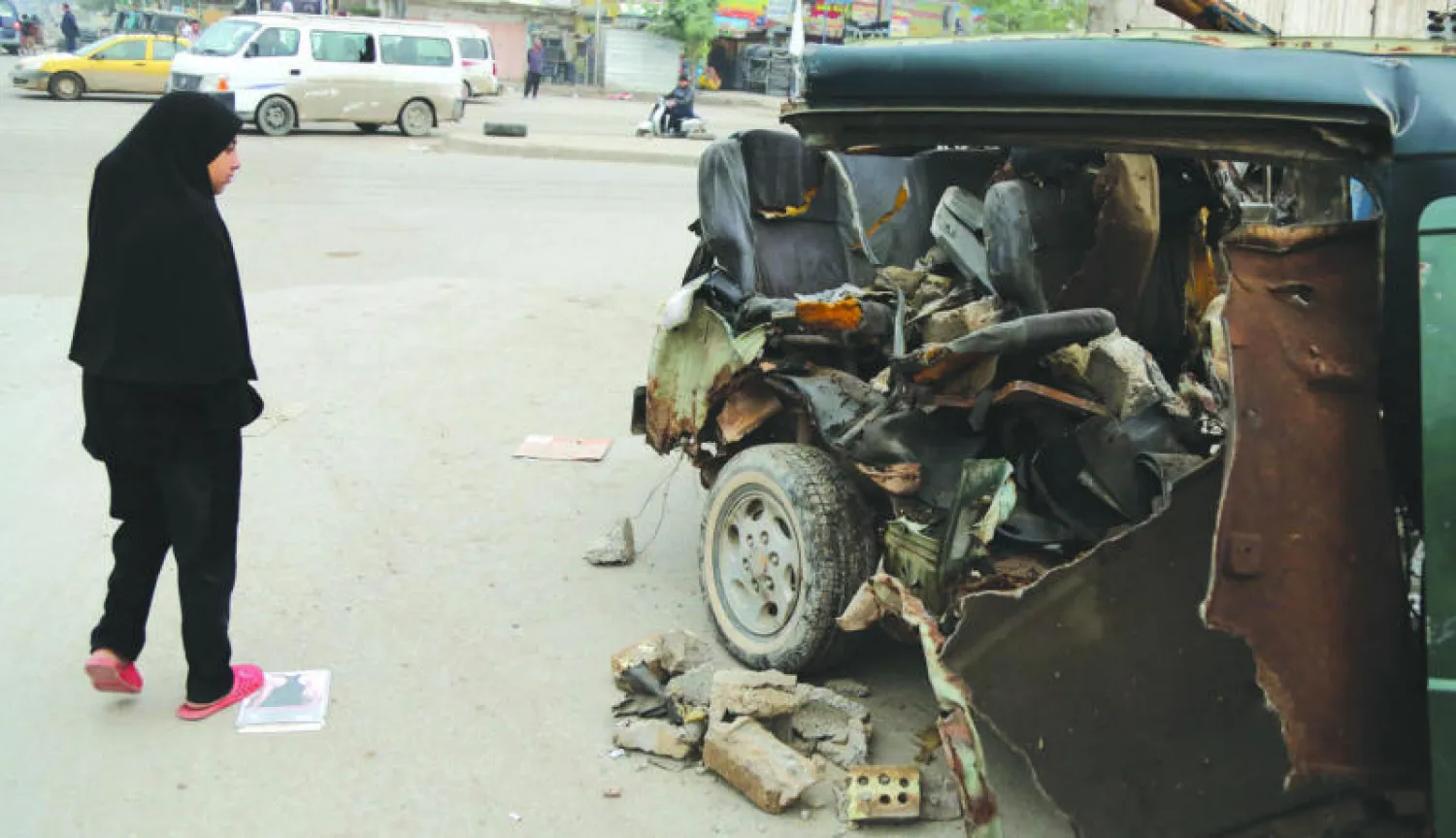 عراقيون يعاينون أمس حطام سيارة في موقع انفجار سيارة مفخخة في مدينة الصدر ببغداد أول من أمس (أ.ب)