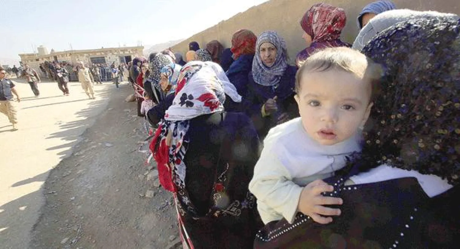 طابور من اللاجئين السوريين الهاربين من جحيم معارك القلمون إلى عرسال اللبنانية أمس (أ.ف.ب)