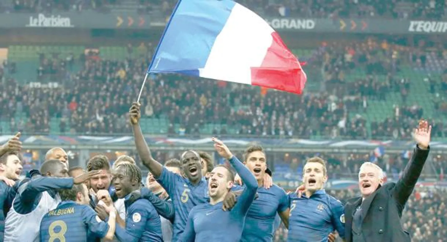 ديشامب مدرب فرنسا (يمين) ولاعبو المنتخب يحتفلون بانتصارهم المثير على أوكرانيا والتأهل للمونديال (رويترز)