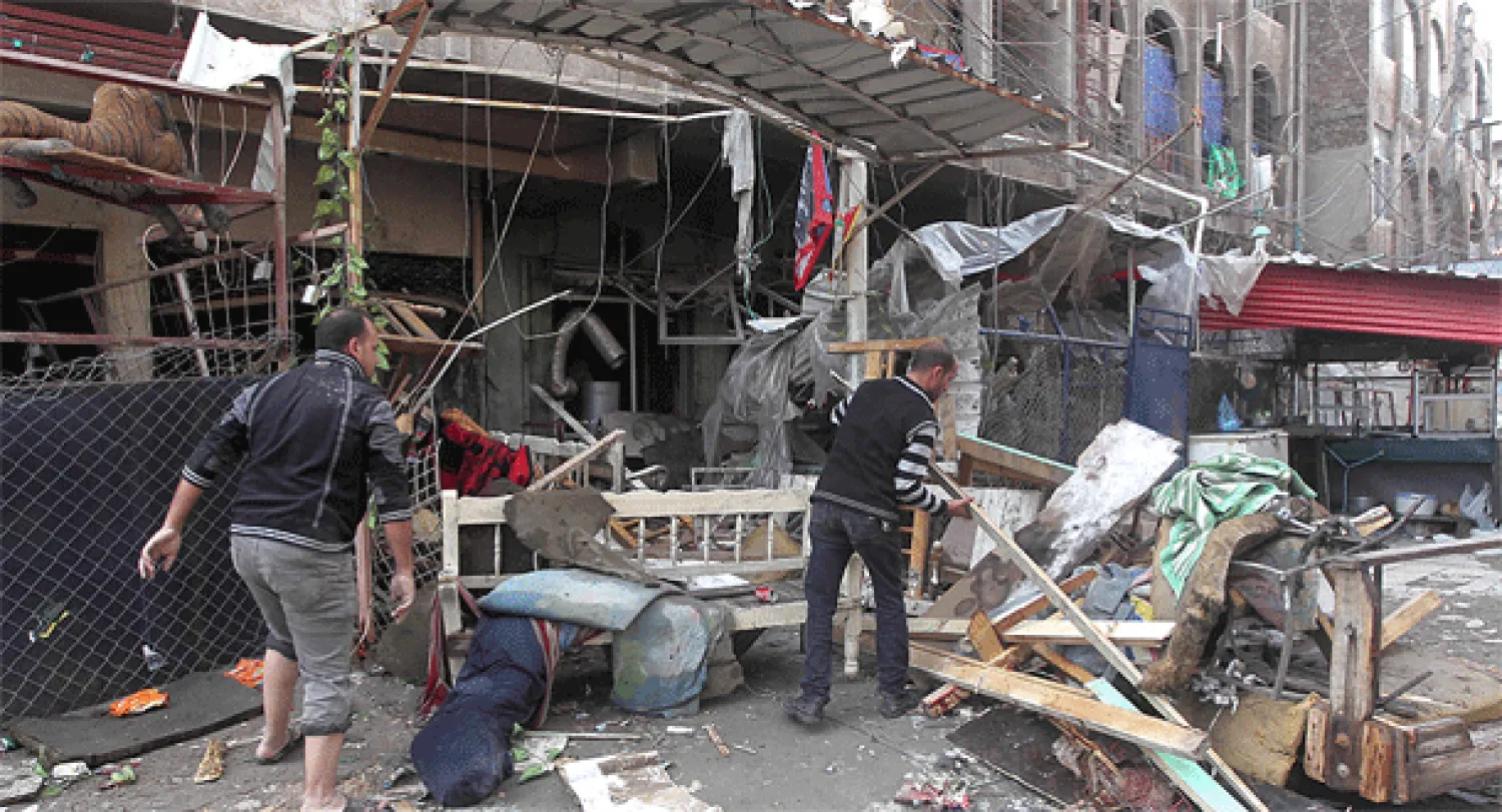 عراقيان ينظفان آثار الدمار الذي أحدثه تفجير خلف قتلى وجرحى