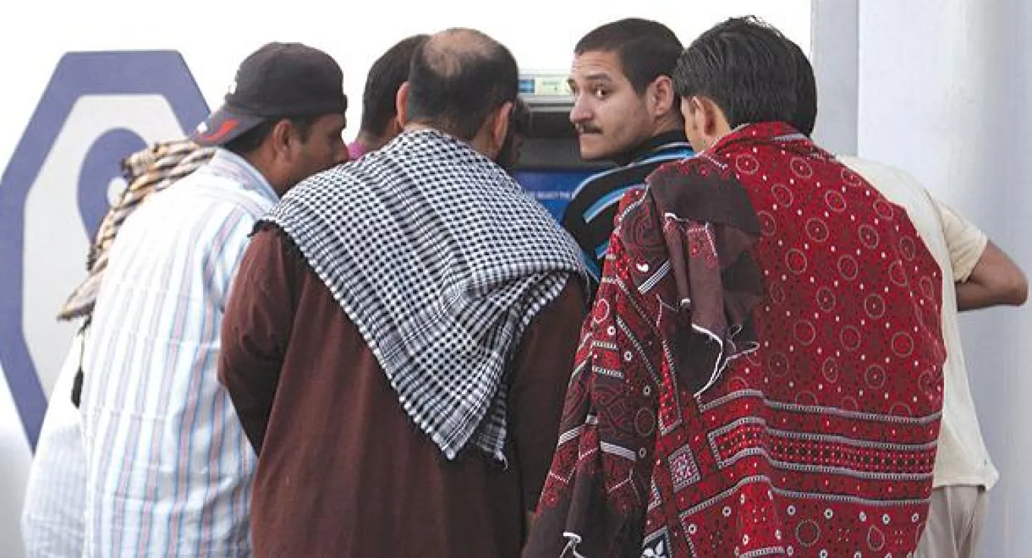 يقوم أحد هؤلاء العمال بحوالات بنكية لصالح عمال عجزوا عن فتح حسابات خاصة لهم كونهم يعملون  بصورة غير نظامية وهو جزء من الاقتصاد الخفي (تصوير: خالد الخميس)