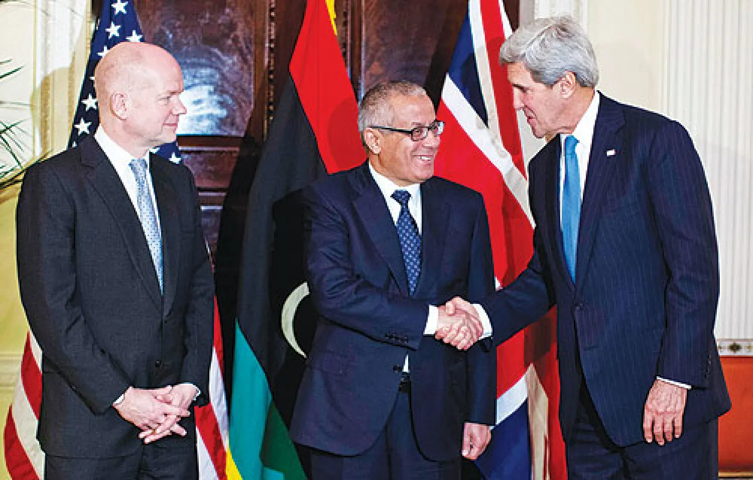 جون كيري يصافح علي زيدان في حضور وليام هيغ في مقر اقامة السفير الاميركي في لندن أمس (رويترز)