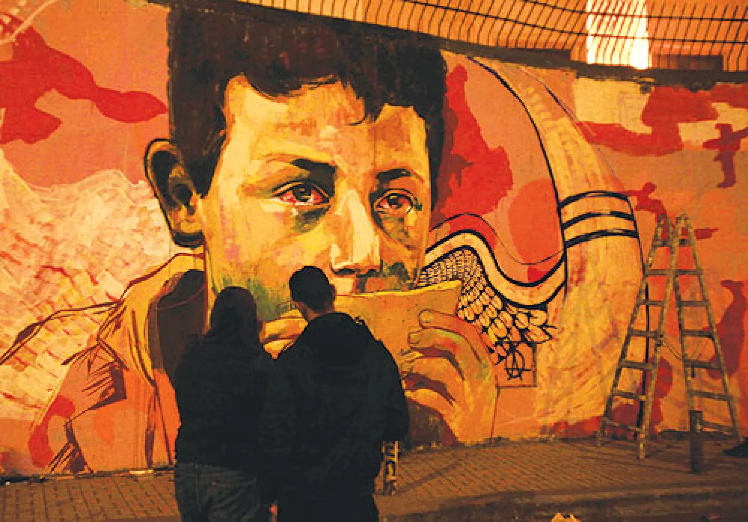 مصريان يشاهدان جدارية لإحياء ذكرى ضحايا العنف في شارع محمد محمود وسط القاهرة أمس (رويترز)