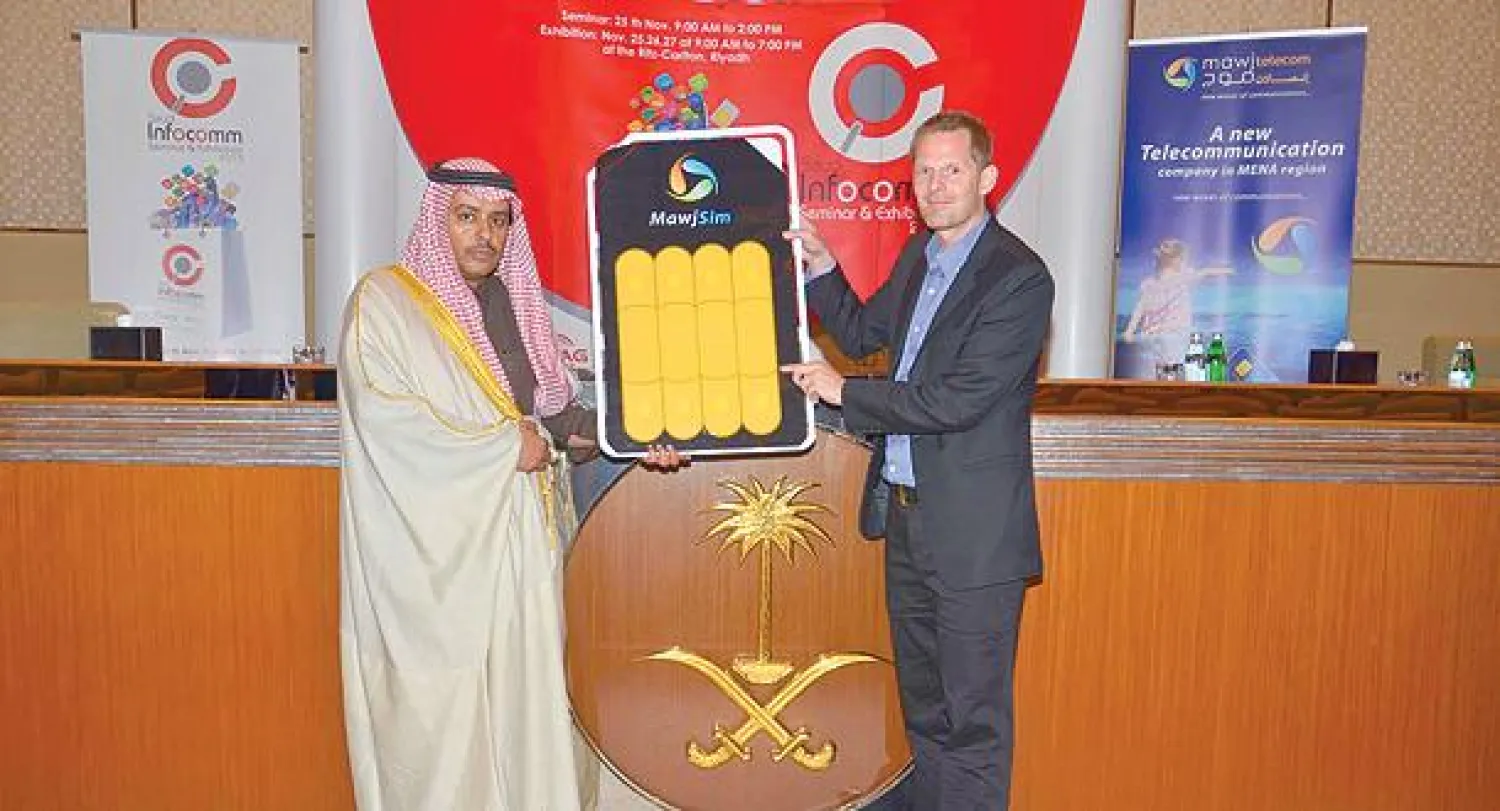 رئيس مجلس الأعمال السعودي - السنغافوري يستعرض الشريحة اللاصقة مع الرئيس التنفيذي لشركة «موج» للاتصالات («الشرق الأوسط»)