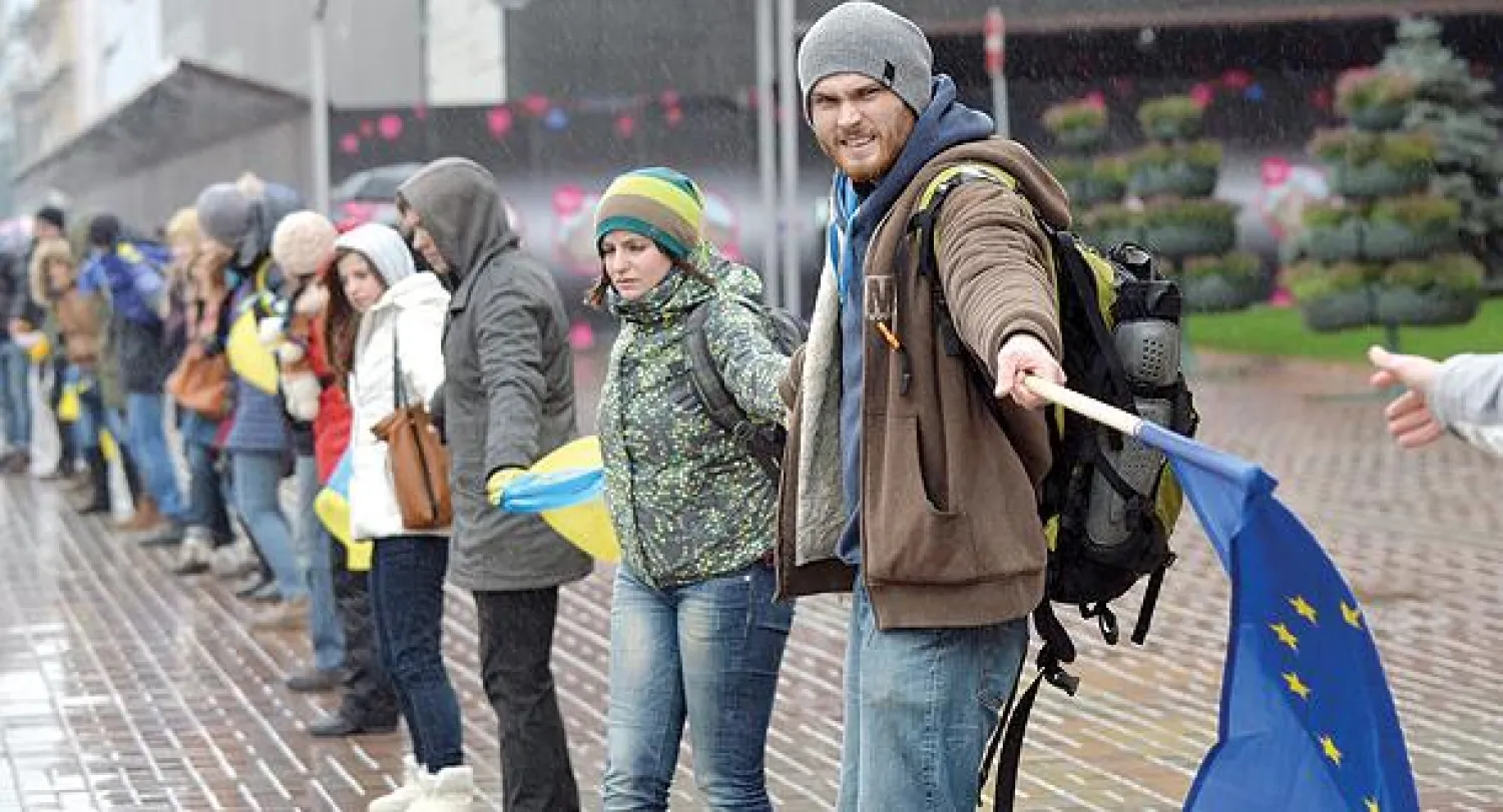 طلاب أوكرانيون يقفون في صف واحد يدا في يد تعبيرا عن رغبتهم في التقارب مع أوروبا في العاصمة كييف أمس (أ.ف.ب)