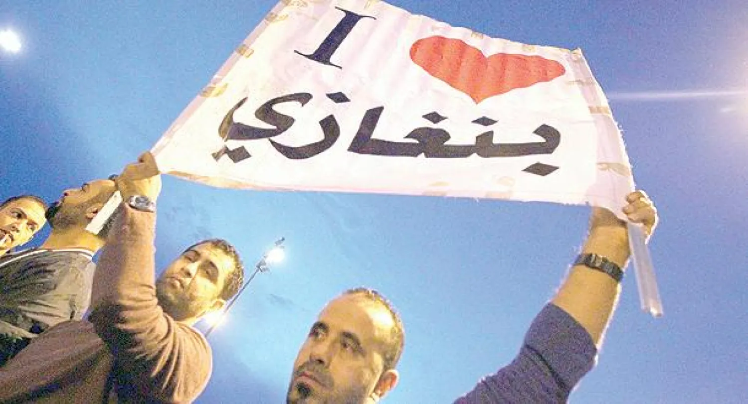 ليبيون يرفعون لافتة ضخمة مكتوبا عليها {أحب بنغازي} أثناء تظاهرهم في بنغازي أمس (أ.ف.ب)